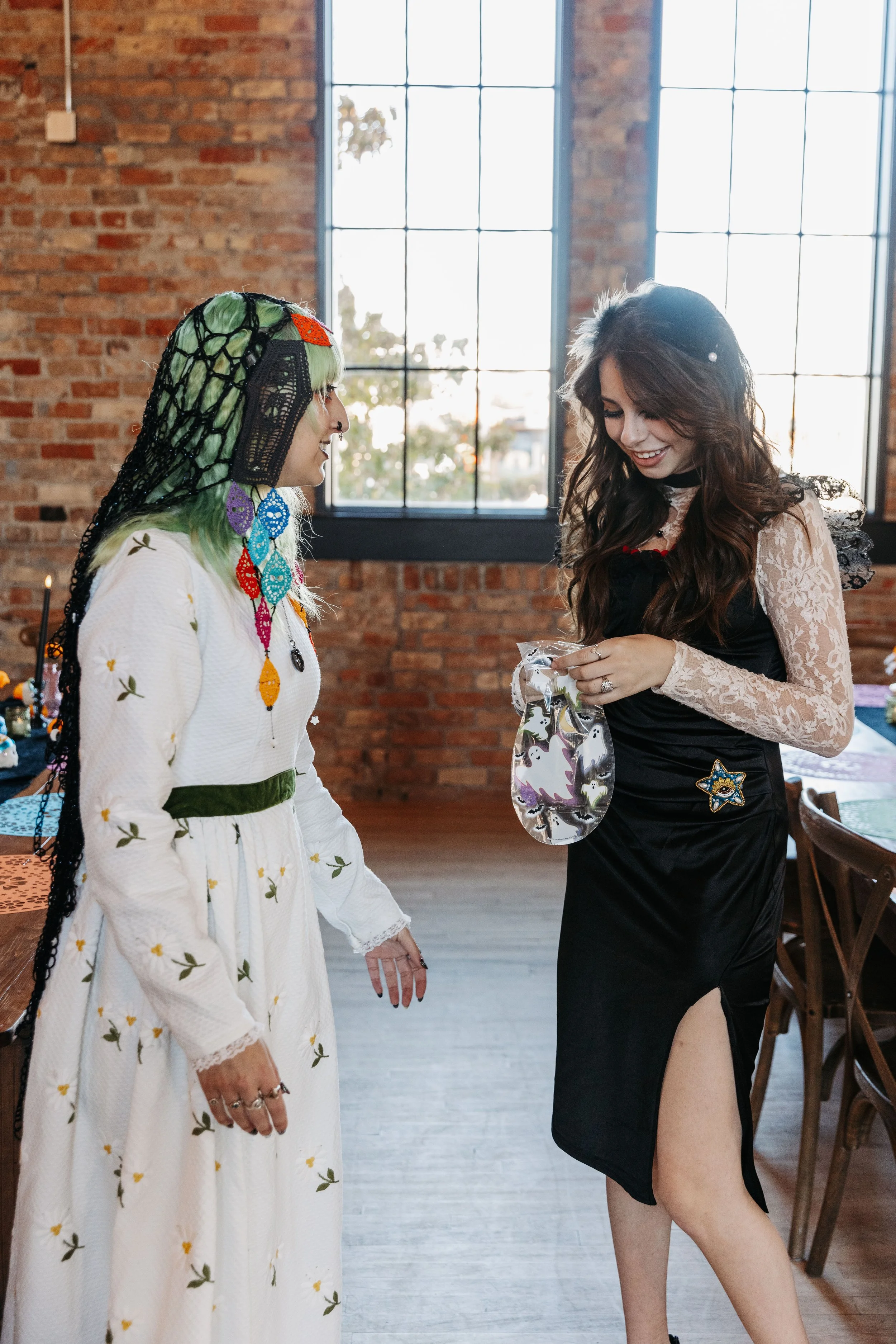 Bride in a floral embroidered wedding dress smiles while receiving a small gift from a guest during a wedding celebration at Crescent Hall.