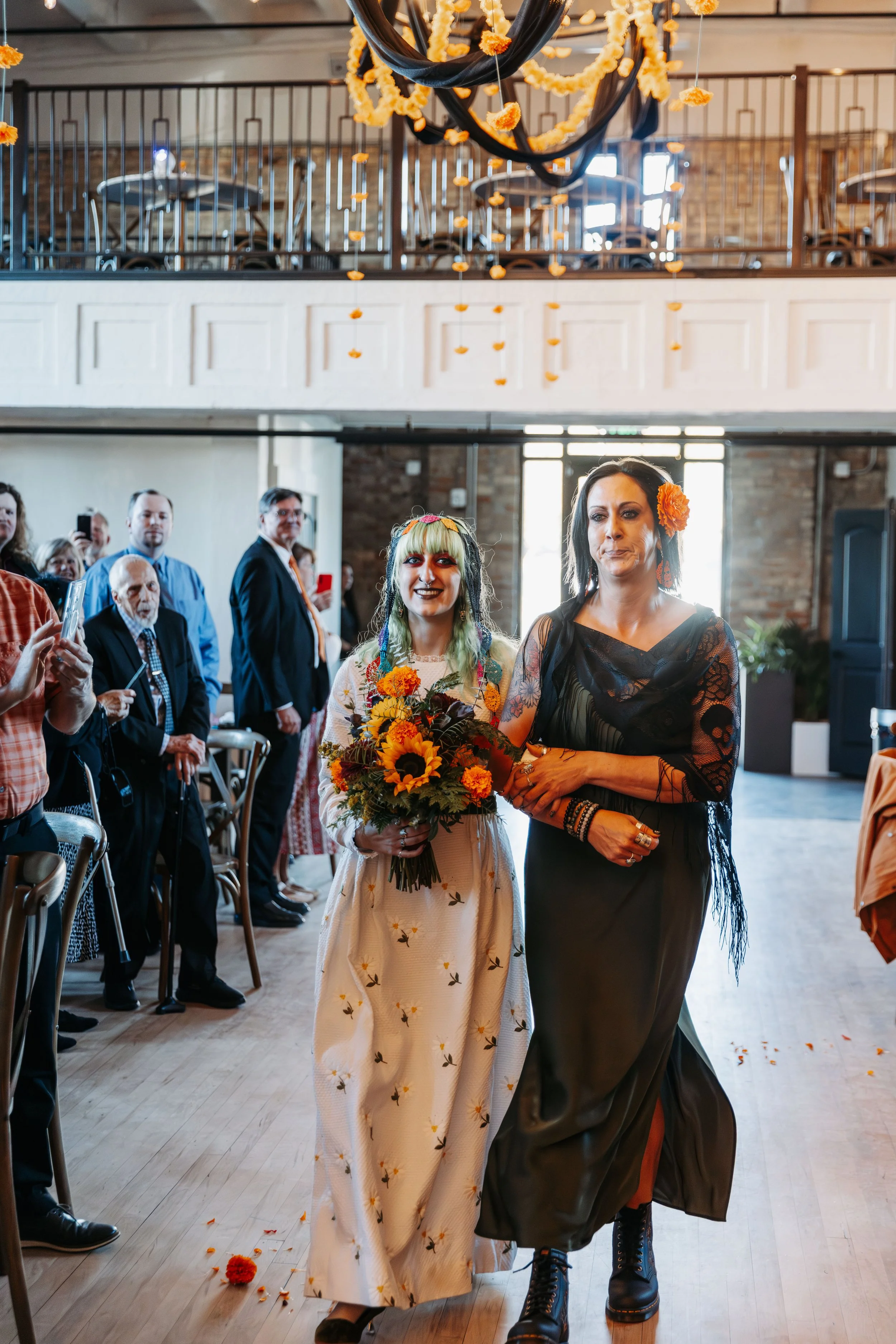 Bride carrying a sunflower bouquet walks down the aisle with her mother during an intimate wedding ceremony at Crescent Hall.