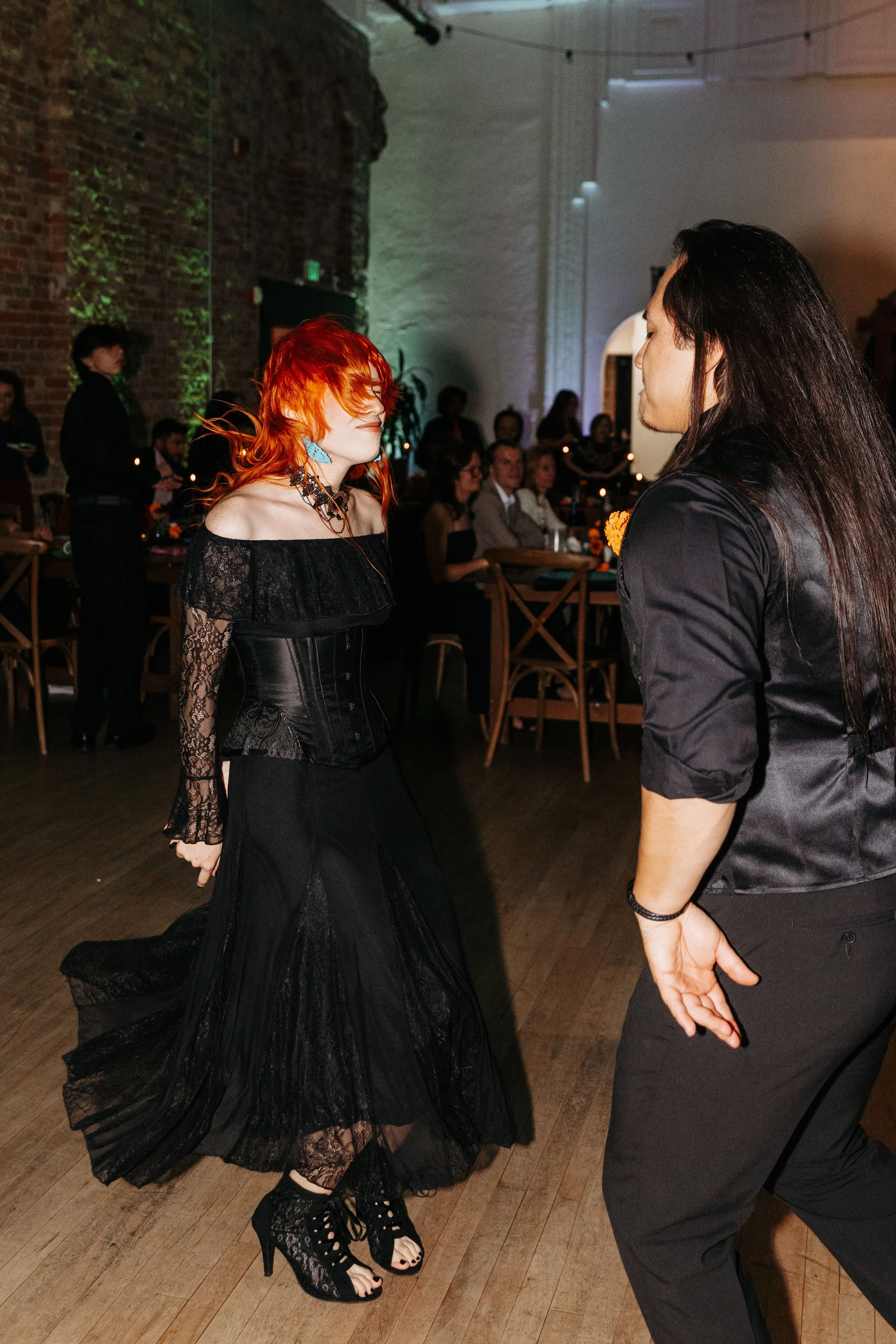Wedding guests dance together on the reception dance floor during an evening celebration filled with music and energy.