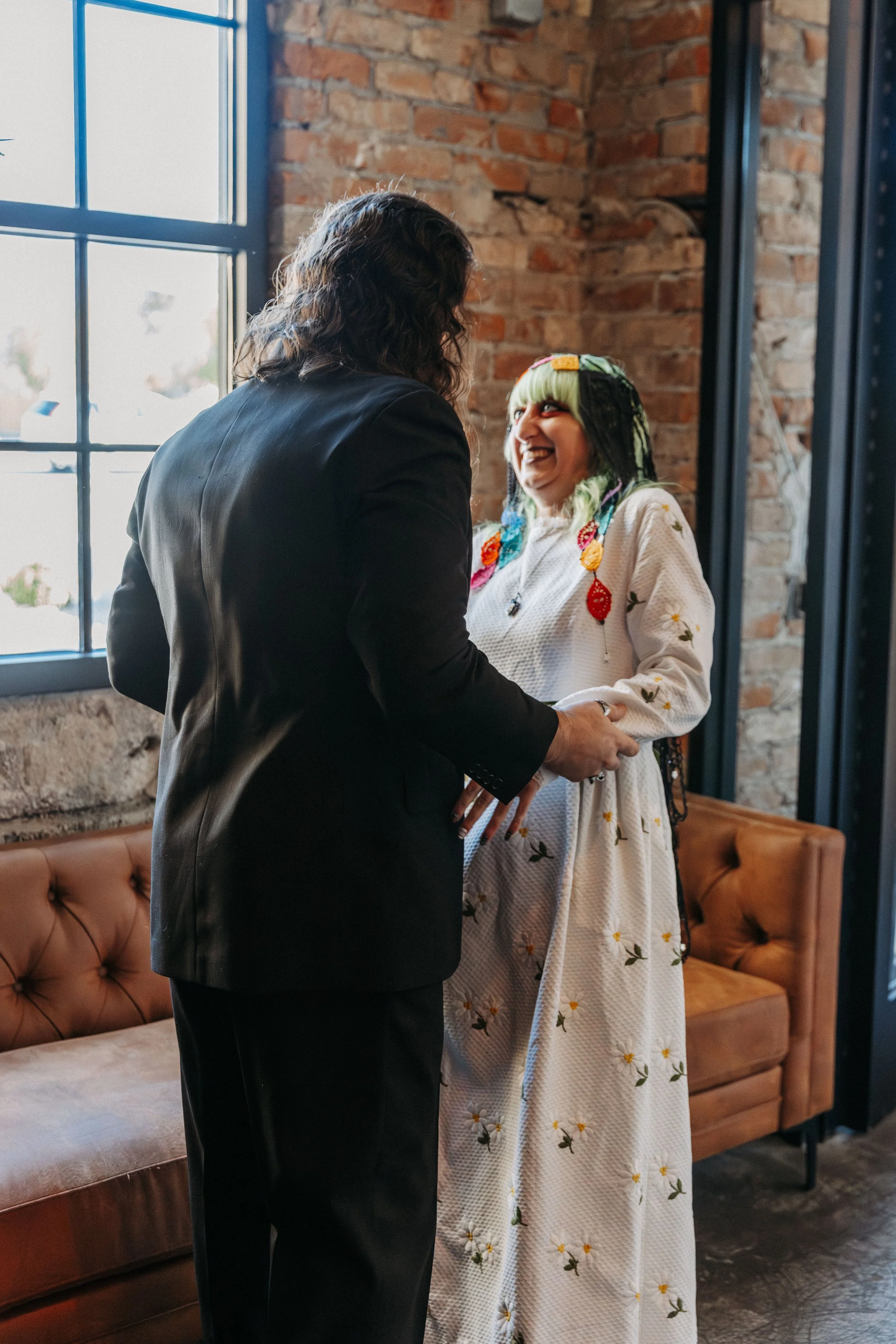 Bride laughs with excitement as she greets her groom during a joyful first look inside an industrial wedding venue.