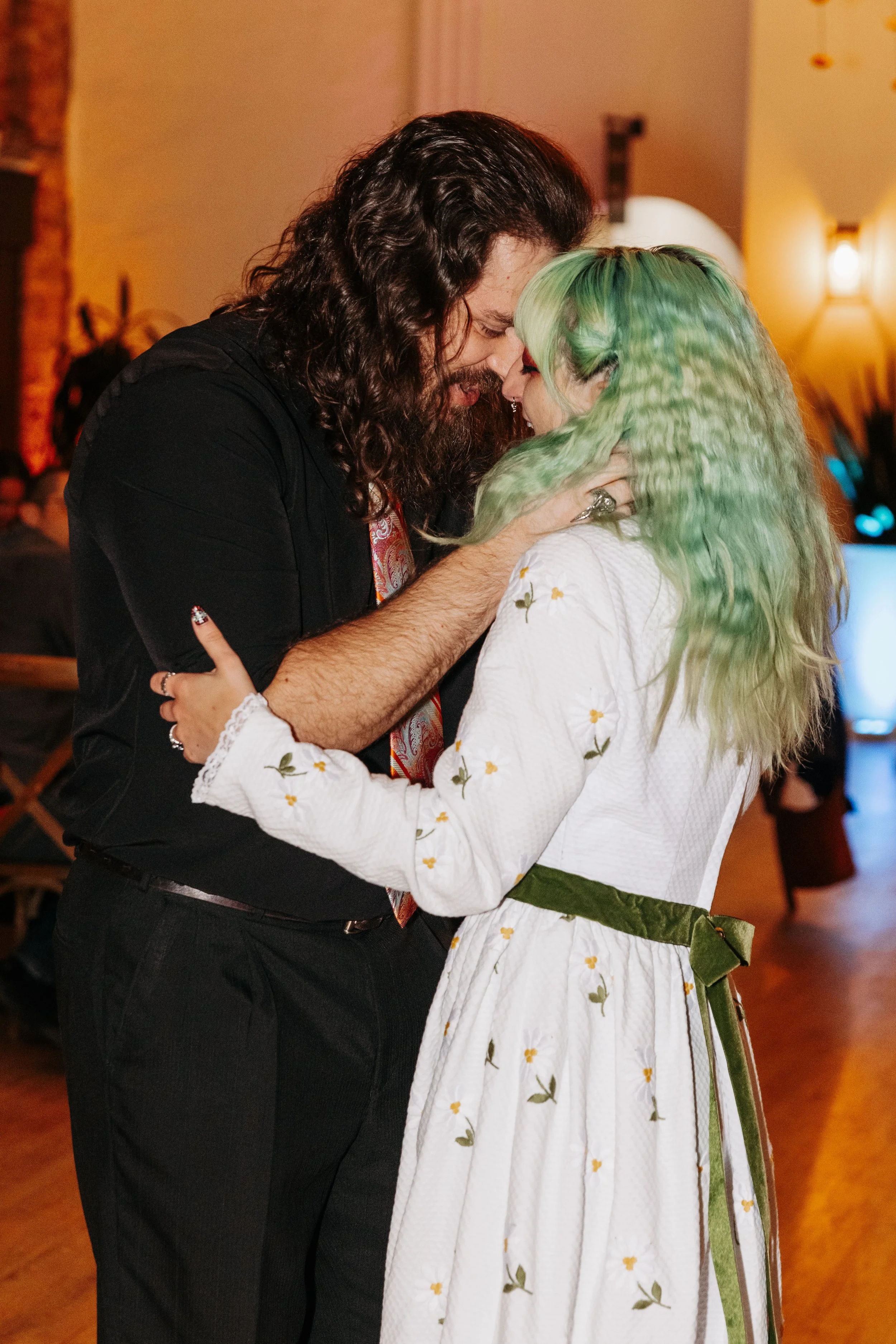 Bride and groom share an intimate dance together during their wedding reception, surrounded by warm lighting and romantic ambiance.