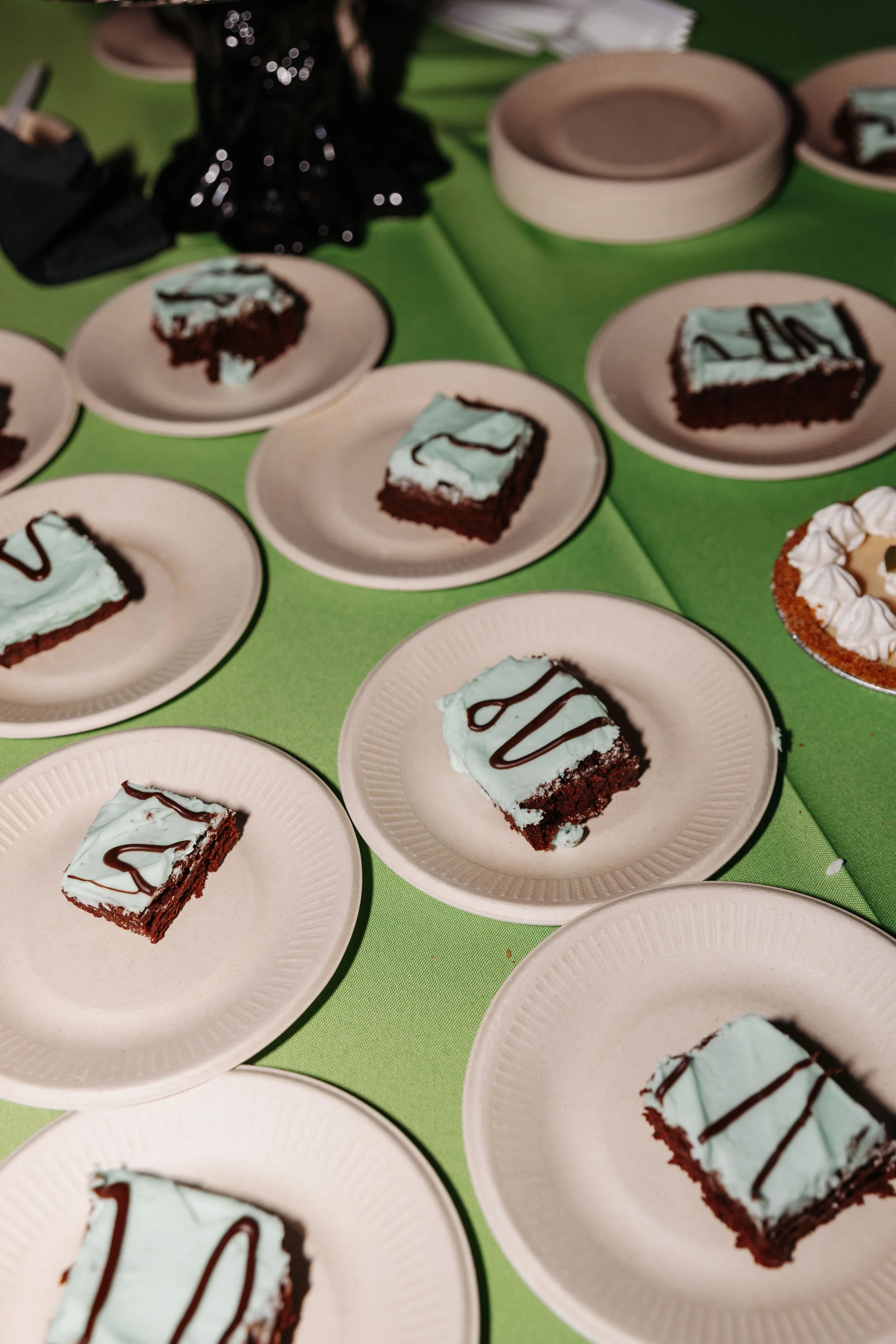 Assorted wedding desserts including frosted brownies and mini pies displayed on a reception dessert table with themed décor.