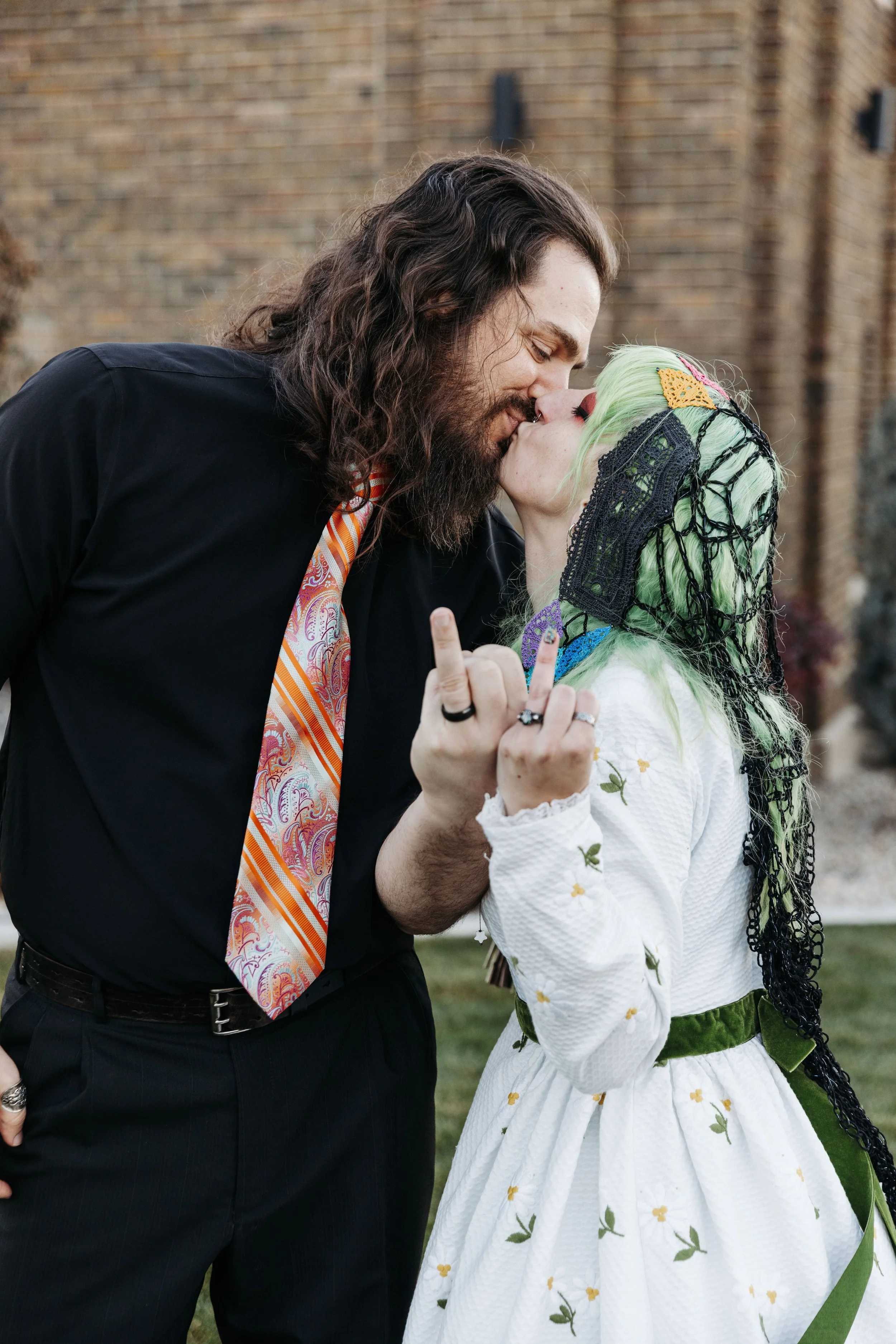 Bride and groom share a kiss while playfully showing their personalities during portraits after their Día de los Muertos-inspired wedding celebration.