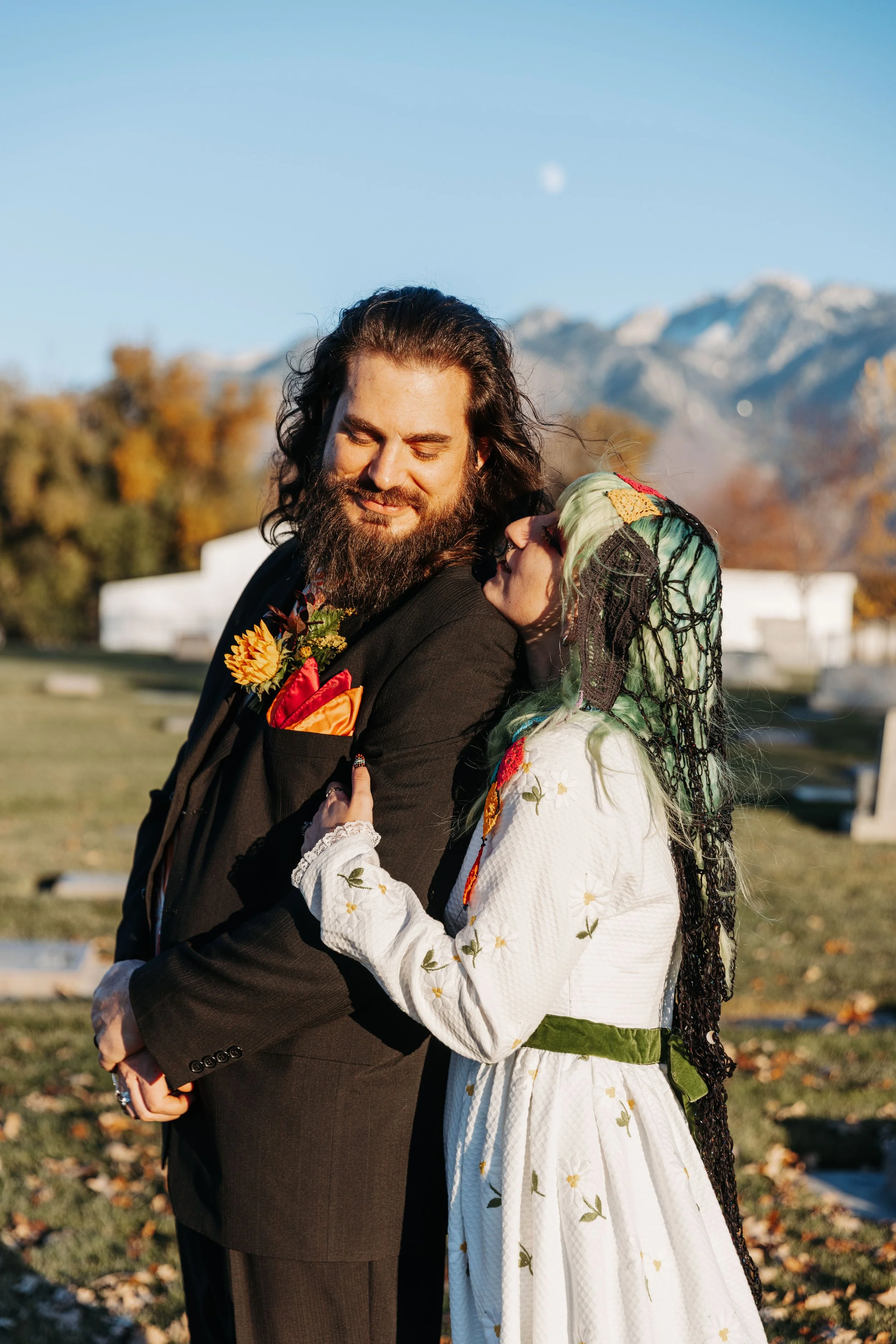 Couple posing together with Utah mountain views in the background, featuring colorful wedding details, alternative styling, and a vibrant fall-inspired color palette.