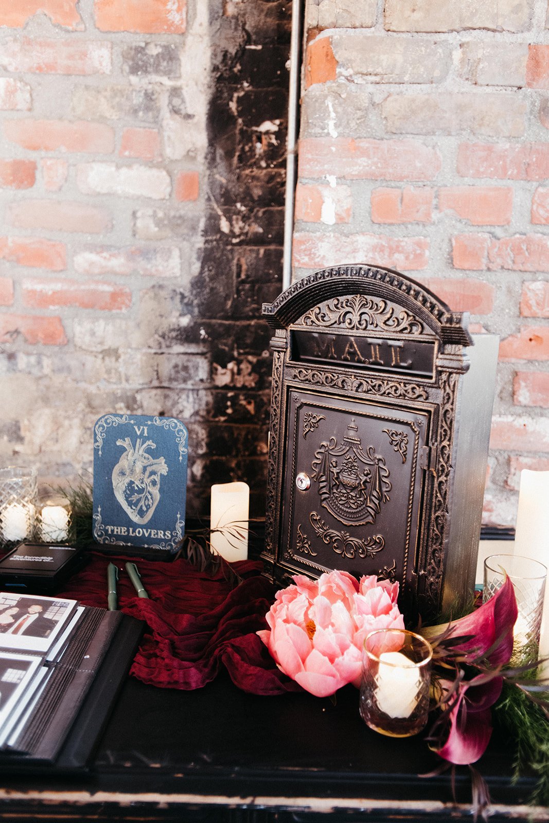 Vintage-style wedding card box displayed with candles, florals, rich burgundy linens, and tarot-inspired décor at a moody wedding reception.
