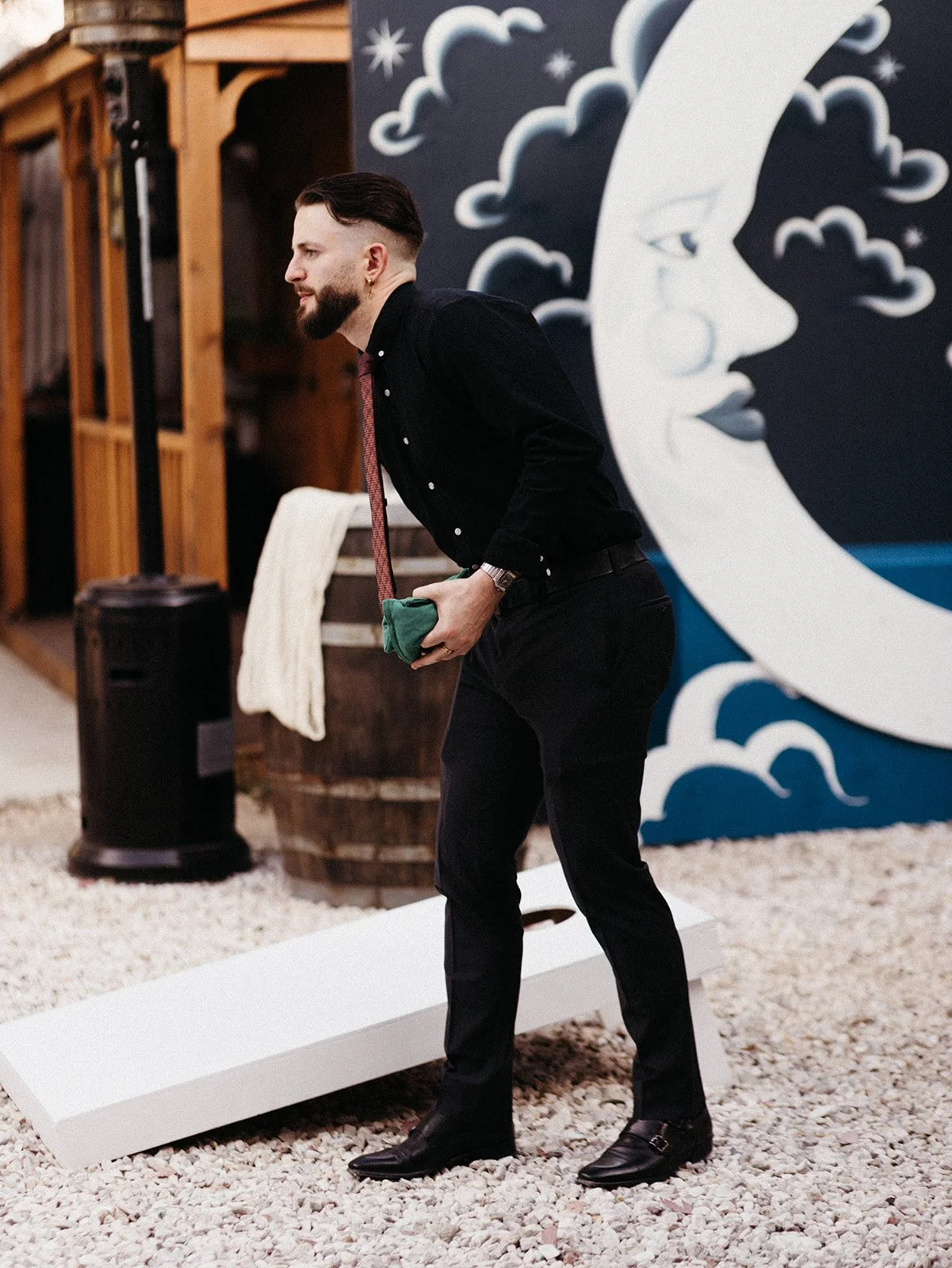 Wedding guest playing cornhole during an outdoor cocktail hour at a personalized Friday the 13th wedding, highlighting interactive guest experiences and relaxed reception activities.