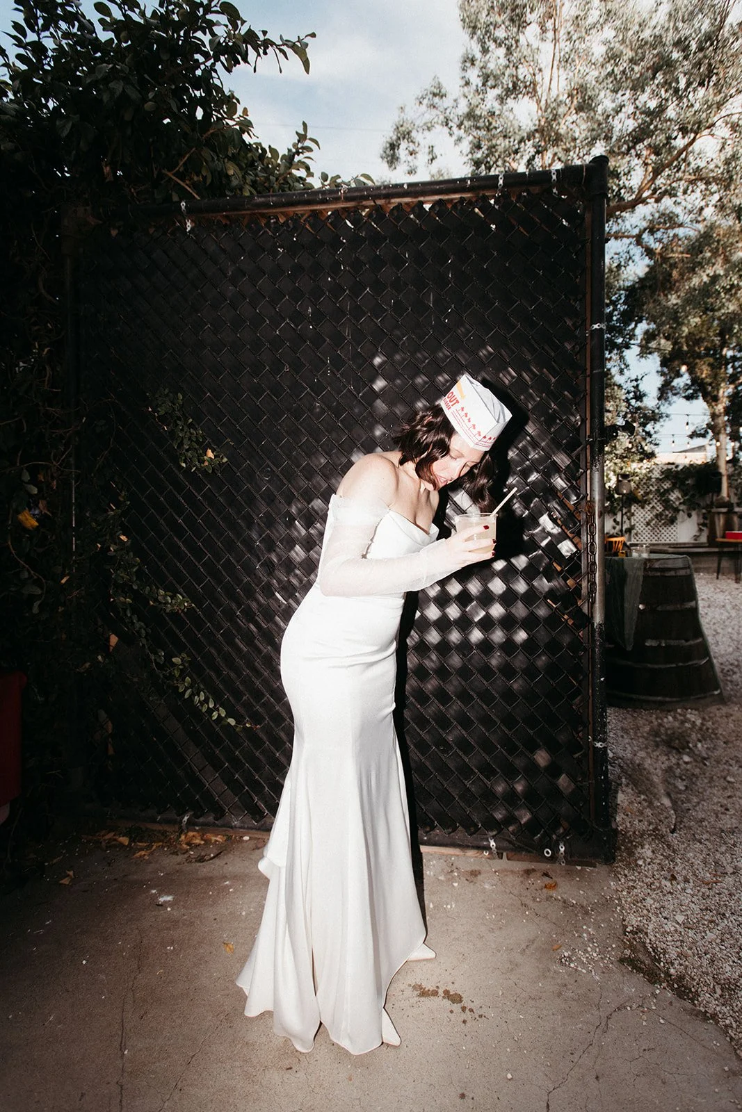 Bride wearing an In-N-Out paper hat enjoys a signature cocktail during the wedding reception, blending playful details with modern wedding style.