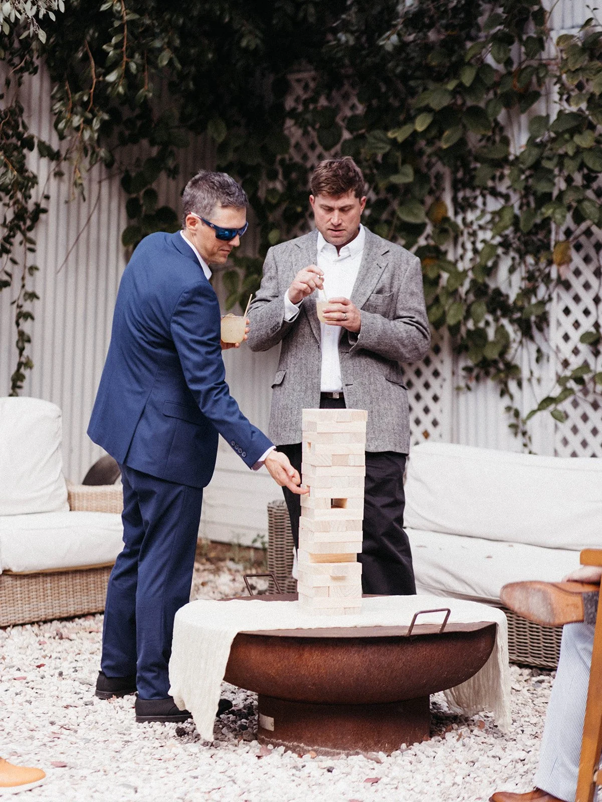 Wedding guests playing giant Jenga during cocktail hour, creating an interactive and welcoming atmosphere at an outdoor wedding reception.