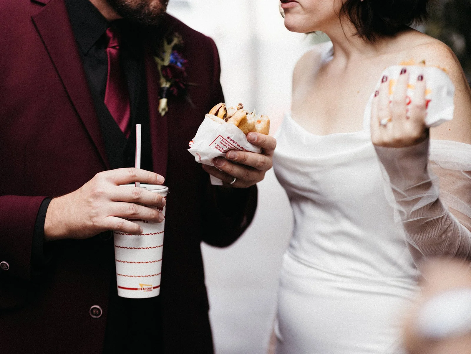 Bride and groom enjoying burgers and milkshakes during a late-night wedding food truck experience, showcasing personalized guest experiences at a nontraditional wedding reception.