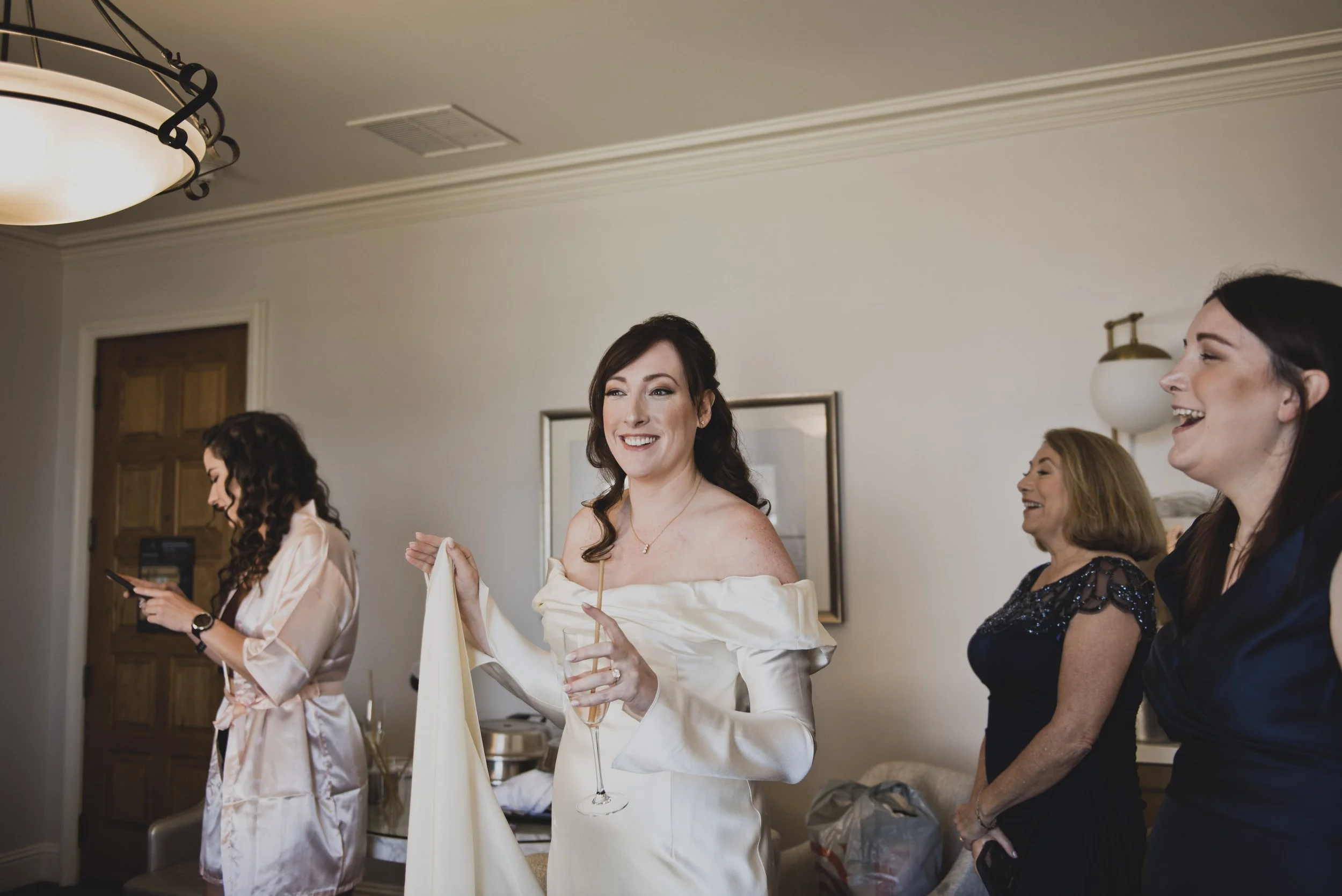 Bride smiling in the mirror while getting ready with her bridal party before a luxury destination wedding ceremony.