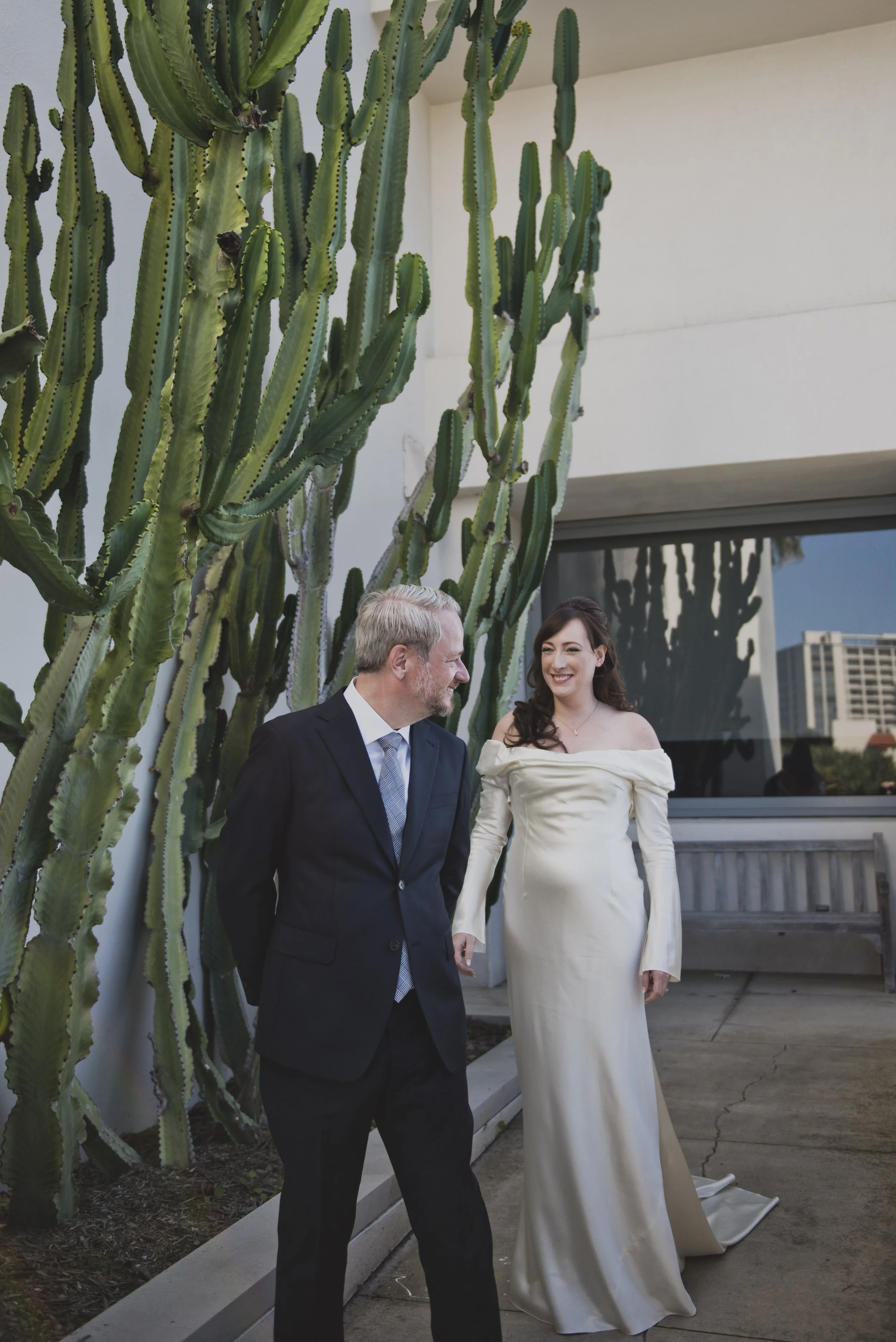 Bride and groom standing beside towering cacti before their destination wedding ceremony, showcasing a relaxed first look experience.
