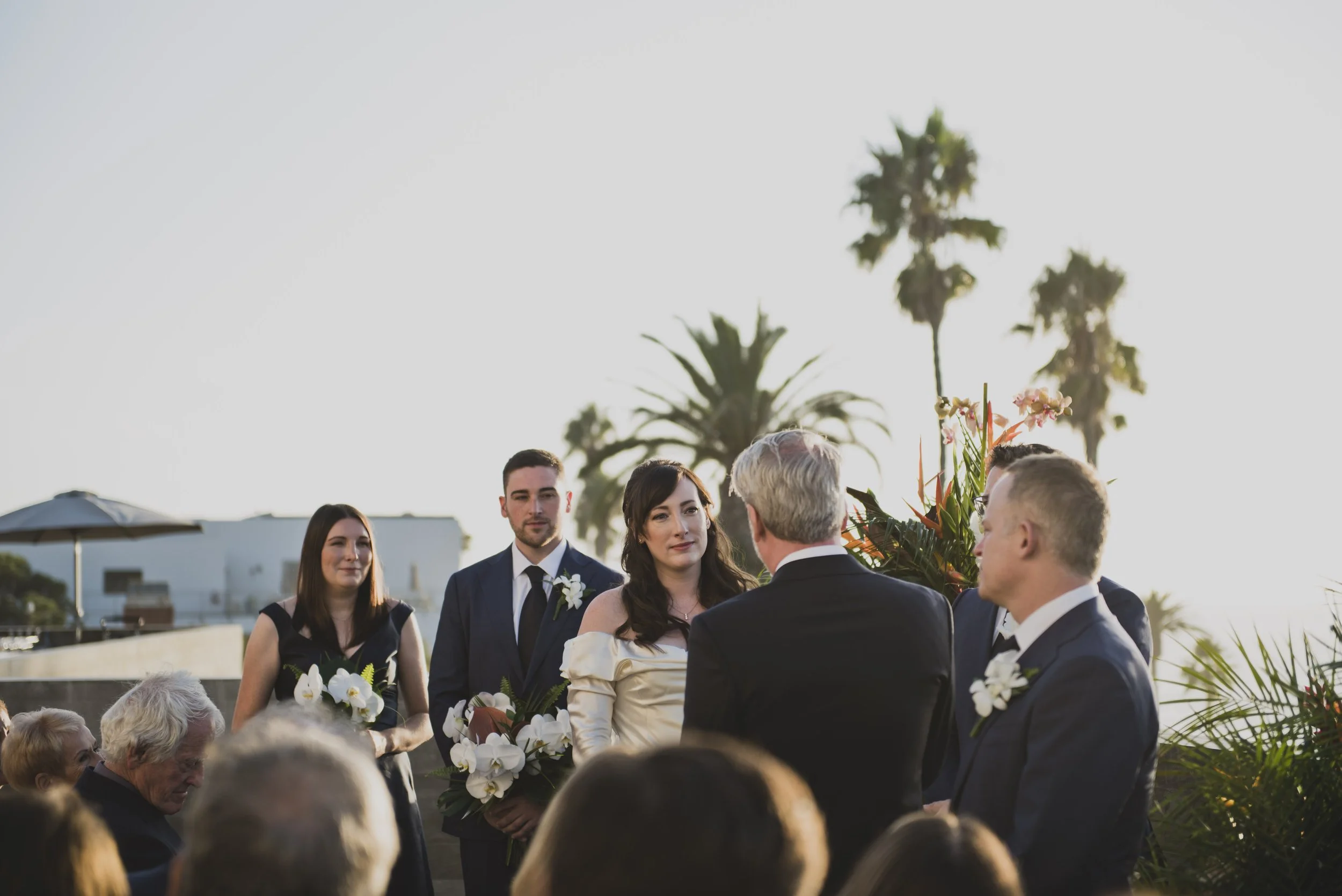 Sunset wedding ceremony while the bride and groom smile at an intimate oceanfront celebration.