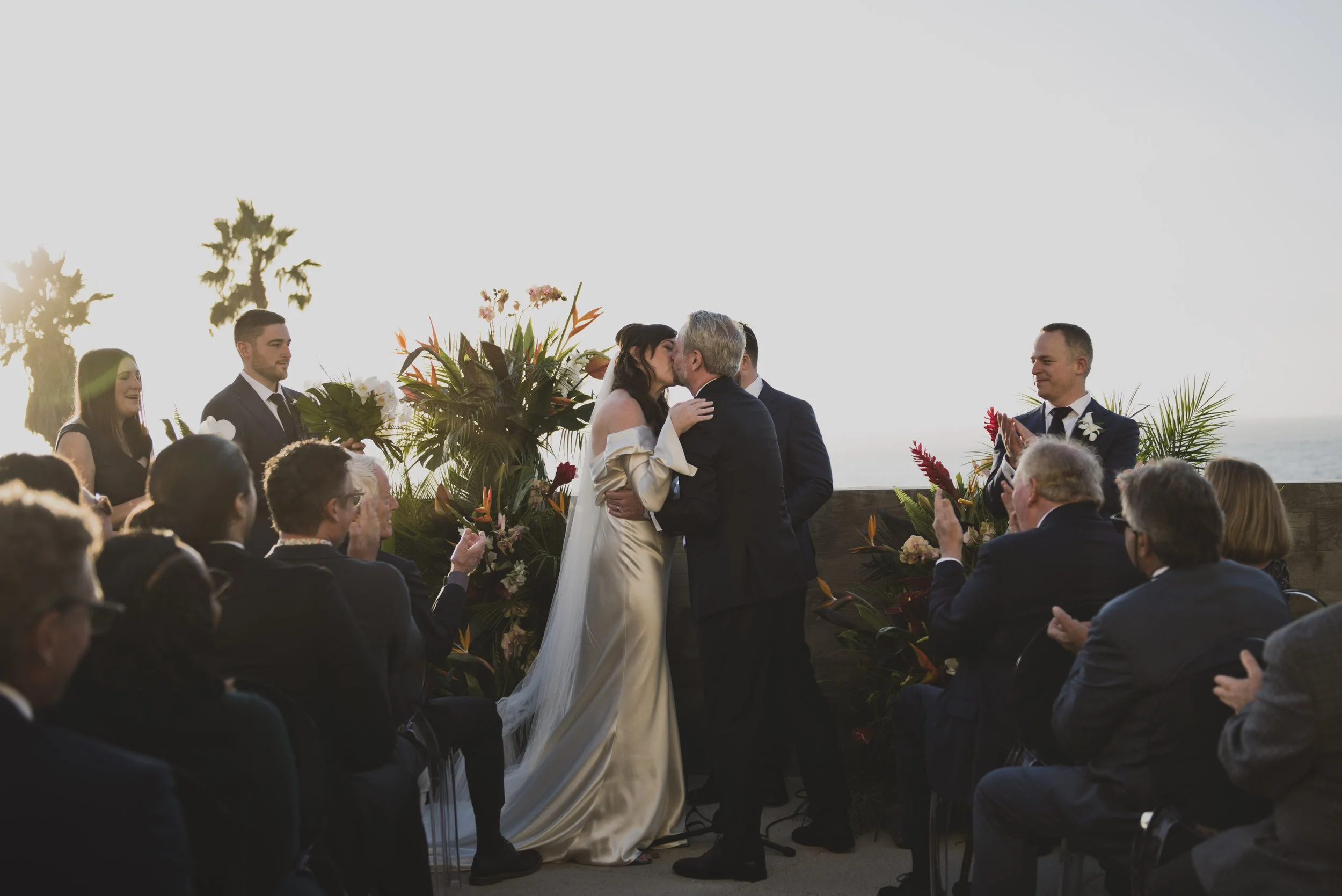 Bride embracing her father after he gives her away during an emotional outdoor wedding ceremony as guests applaud.