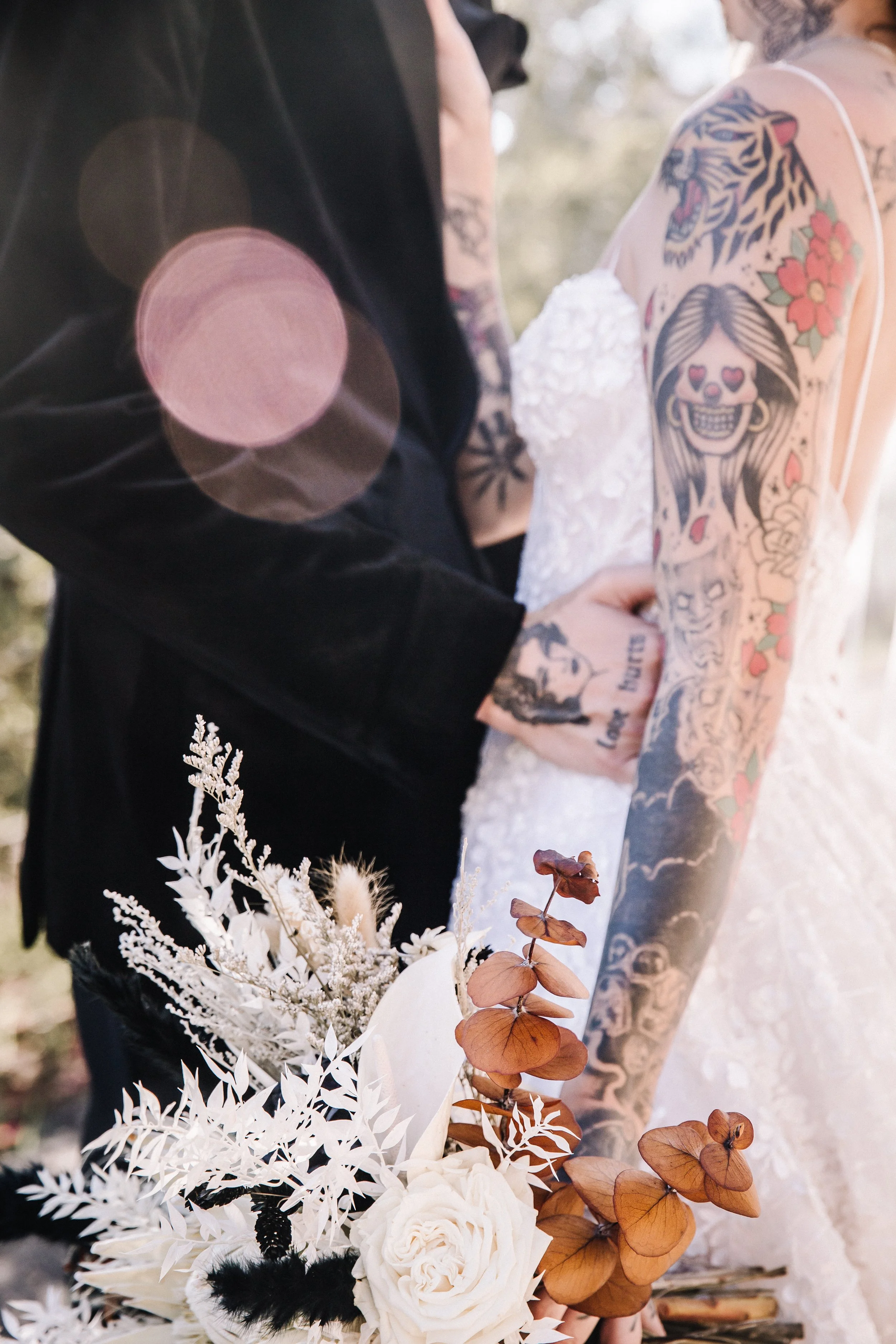 Close-up of white roses, dried botanicals, preserved foliage, and warm-toned eucalyptus arranged in a dark romantic wedding bouquet