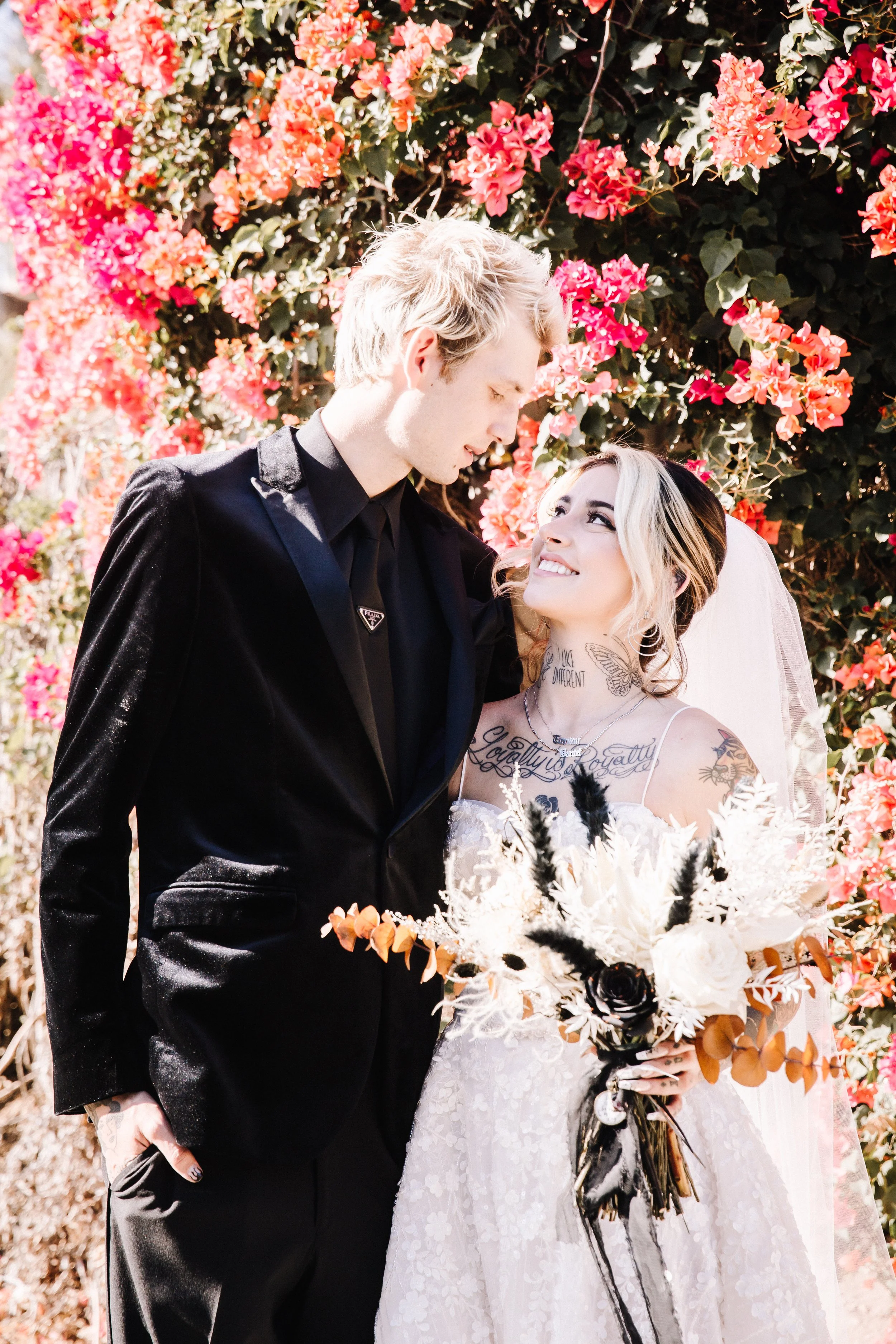 Bride and groom embracing beneath blooming bougainvillea during an intimate alternative wedding portrait session.