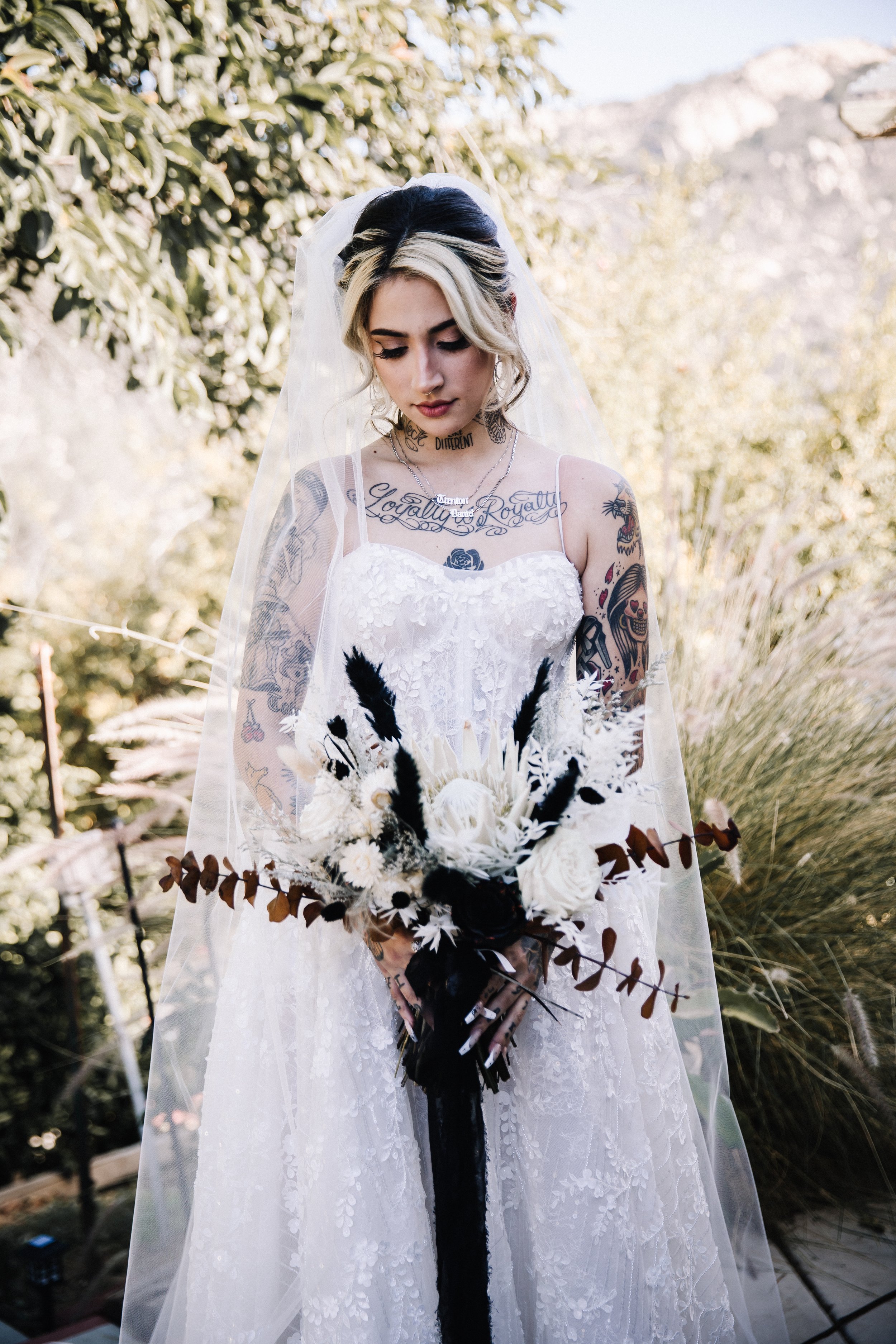 Bride portrait in a textured lace wedding gown holding a white-and-black bouquet during a nontraditional Halloween wedding
