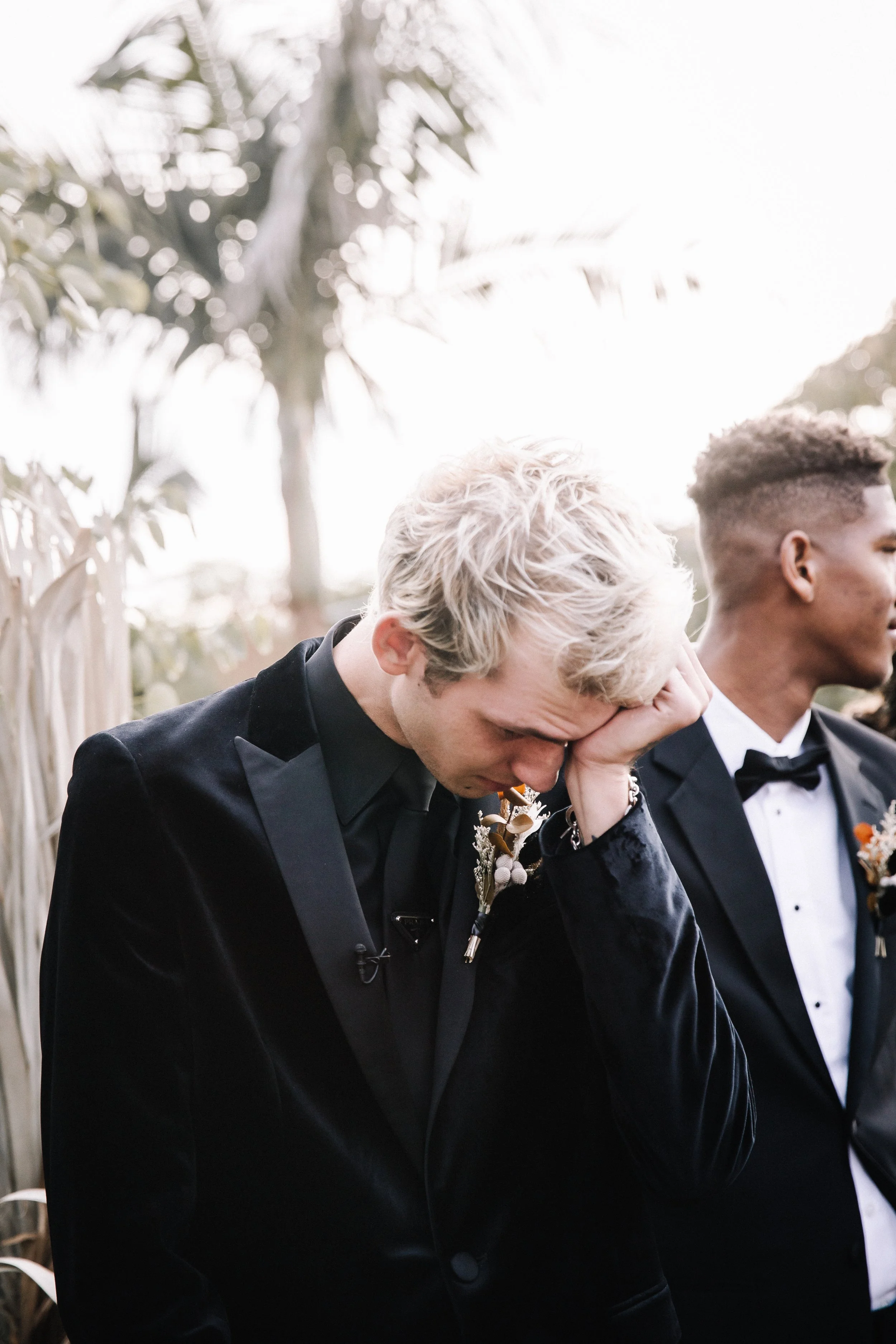 Groom emotional during an intimate outdoor Halloween wedding ceremony surrounded by family, wedding party members, and scenic hillside views.