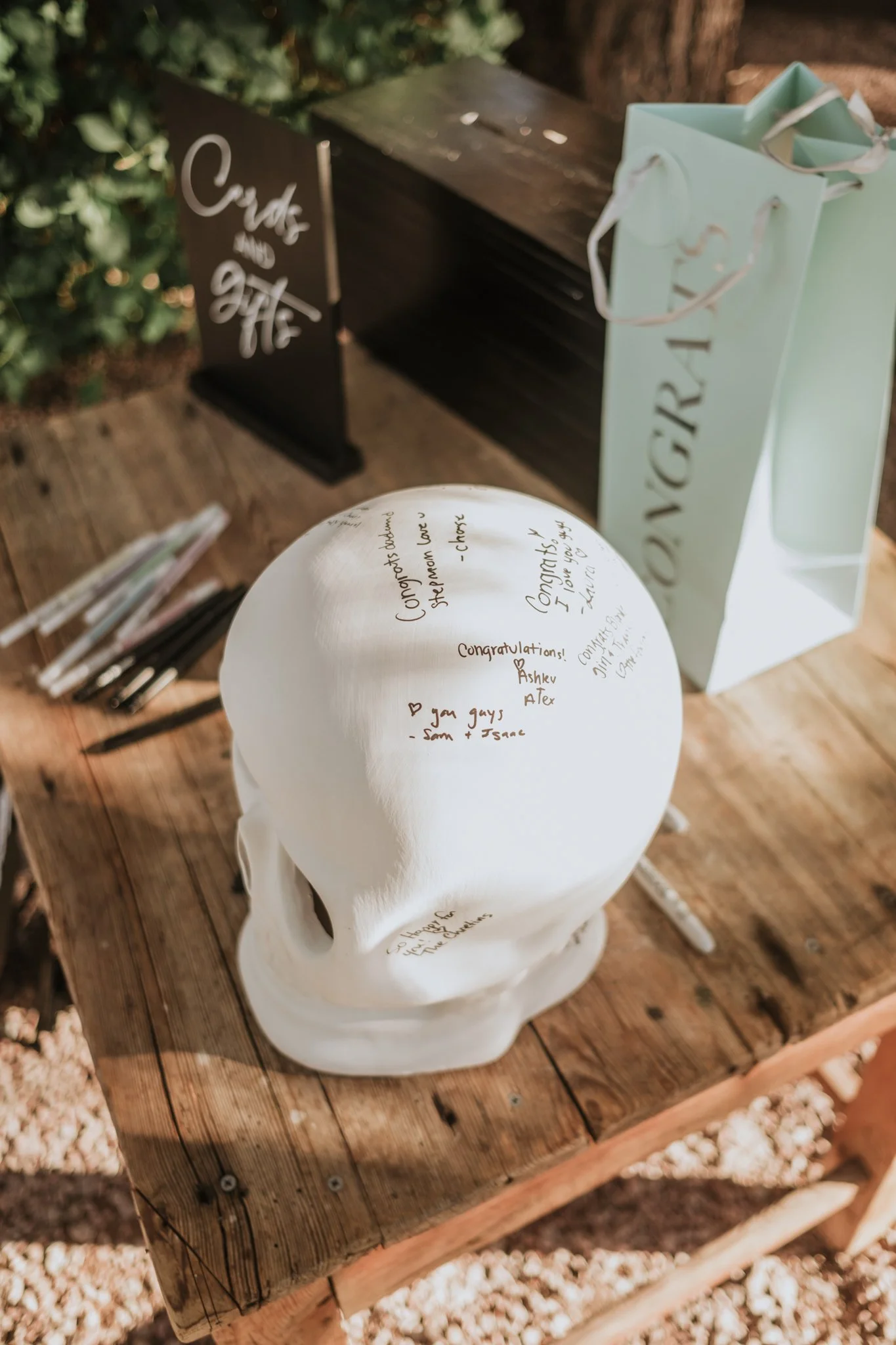 White decorative skull signed by wedding guests displayed as a unique Halloween wedding guest book beside a cards and gifts table.