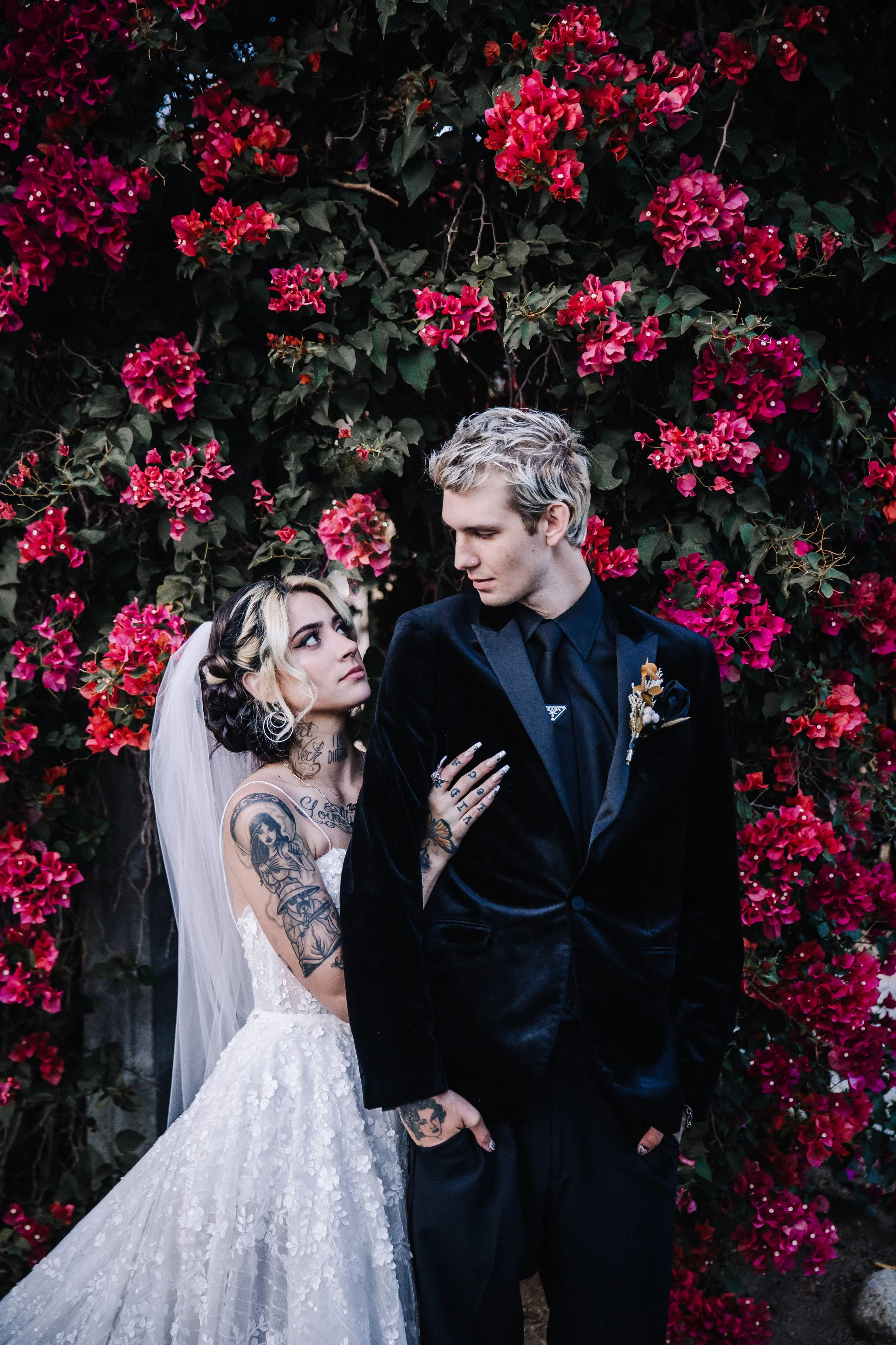 Bride and groom embracing beneath blooming bougainvillea during an intimate alternative wedding portrait session.