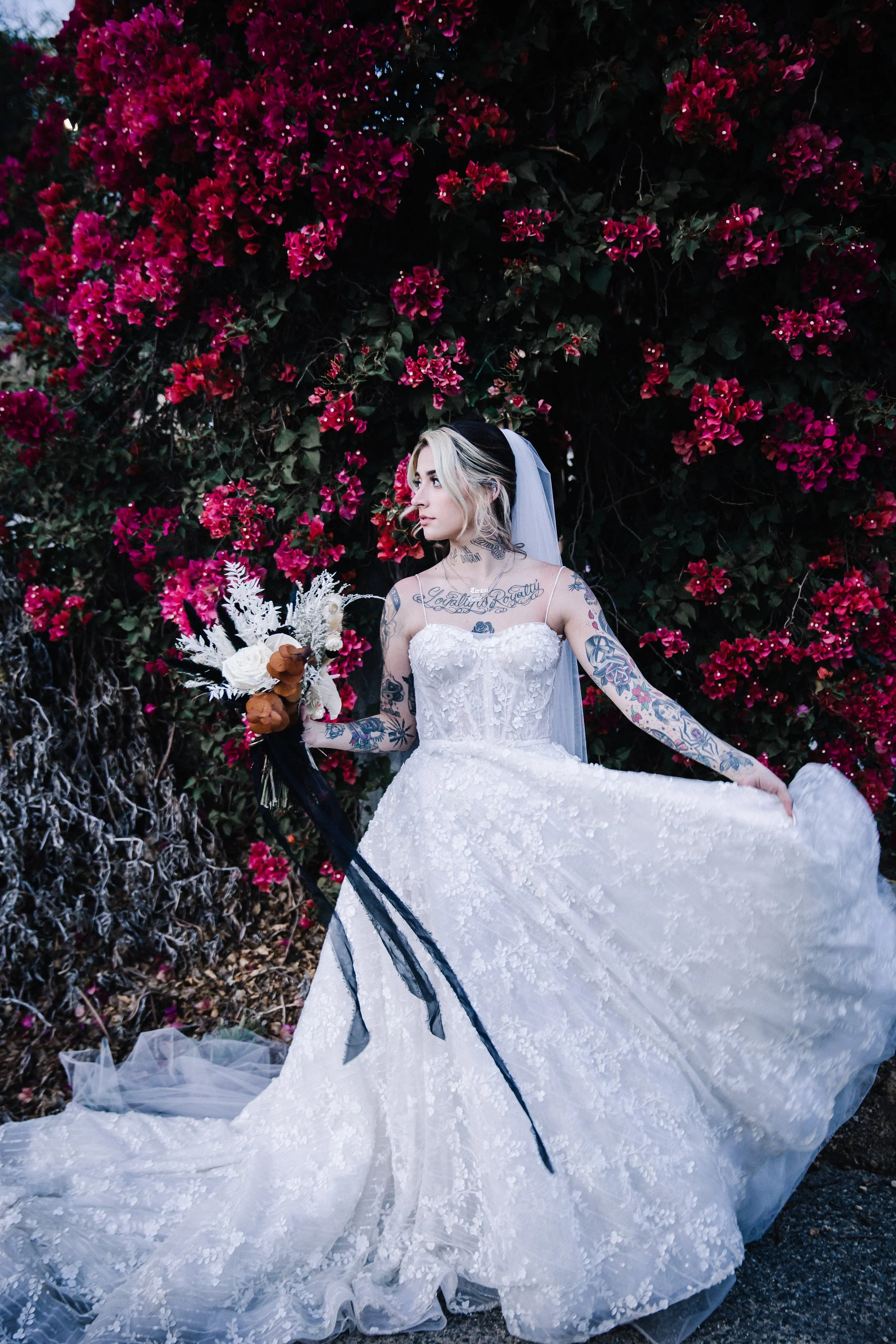 Bride in a lace wedding gown and veil holding a black-and-white bouquet with dried eucalyptus during a nontraditional wedding portrait.