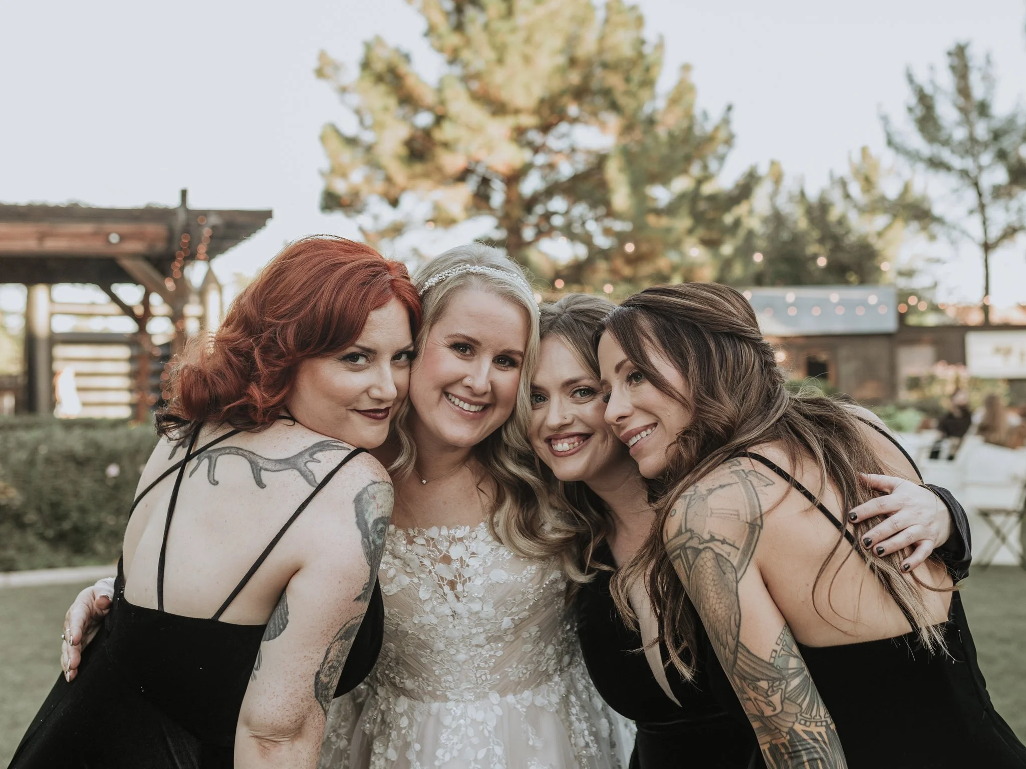 Bride smiling with her bridesmaids during a candid group portrait at an outdoor fall wedding celebration.