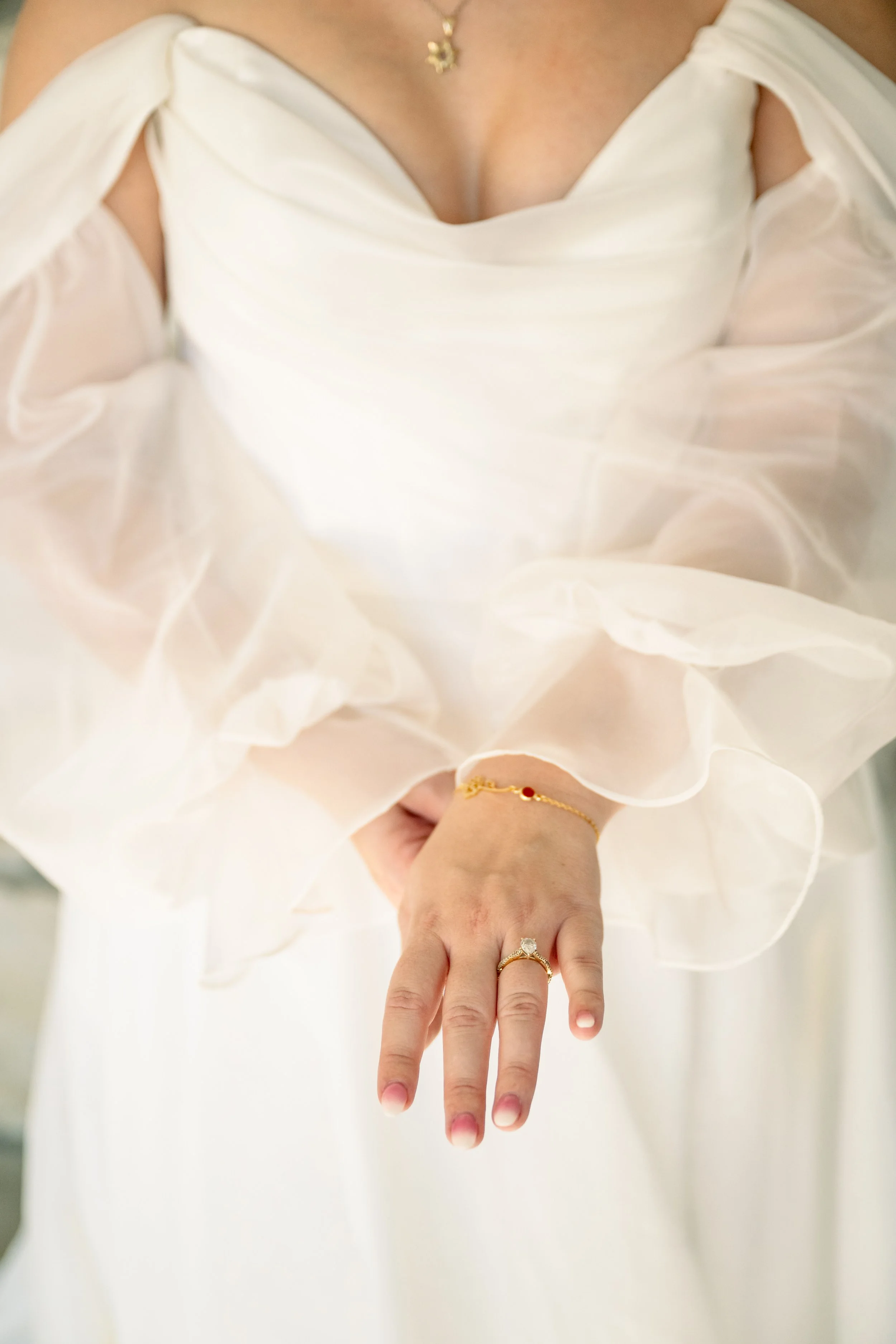 Wedding ring close up in front of dreamy bridal gown