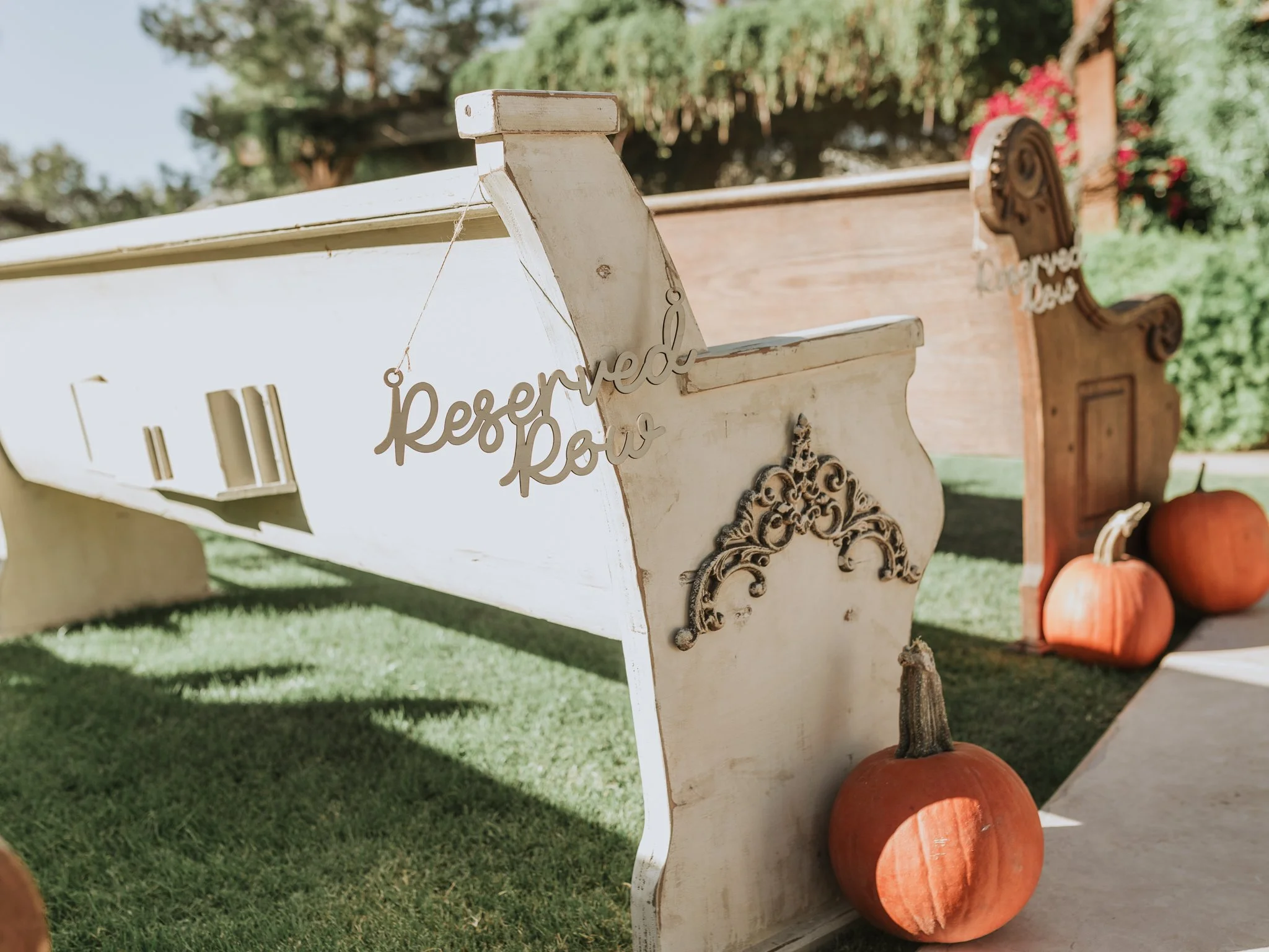 Pumpkin-lined ceremony aisle with vintage benches, designed by a full service wedding planner