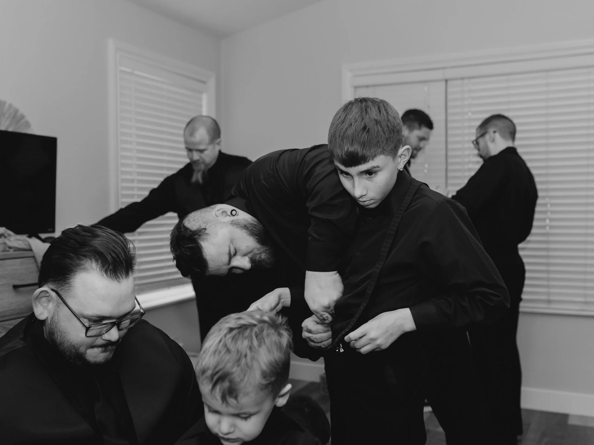 Groom in an all-black suit getting ready before a dark and moody destination wedding