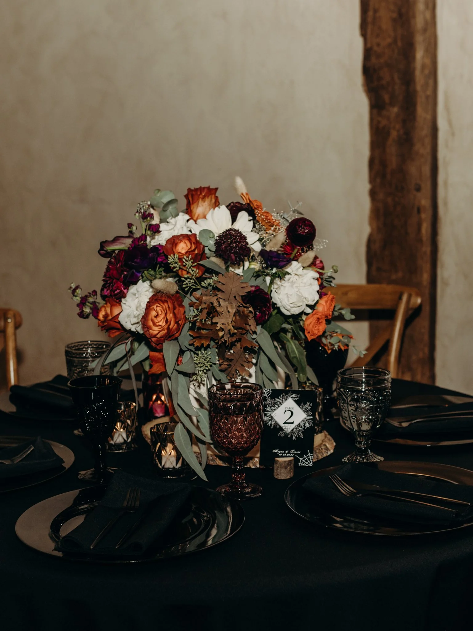 Moody fall centerpiece with black place settings and a spiderweb table number