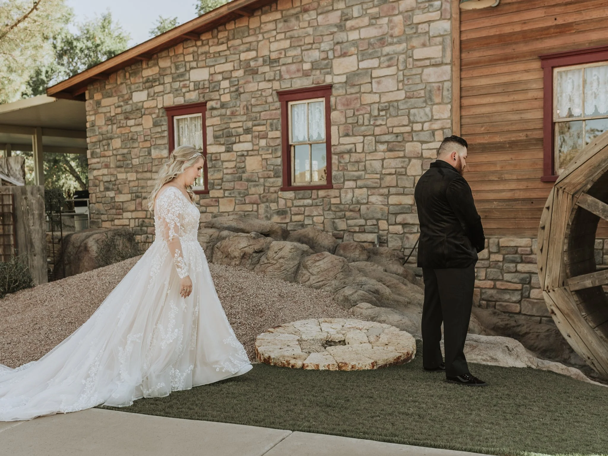 Emotional first look by the stone mill wheel before a Gilbert, Arizona destination wedding