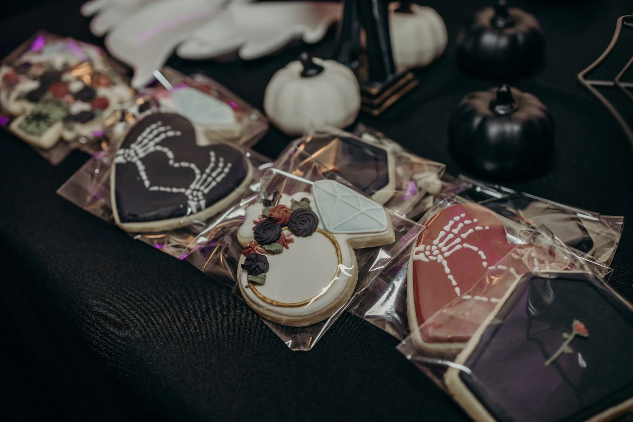 Skeleton-hand and diamond cookies set out as favors at a fall Halloween wedding