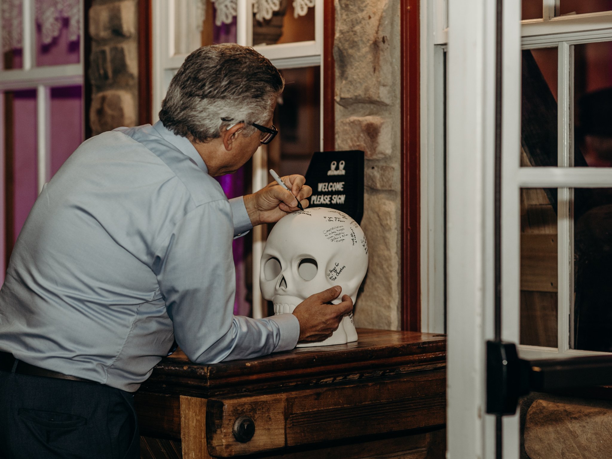 A guest signs the ceramic skull guest book at a Halloween wedding reception