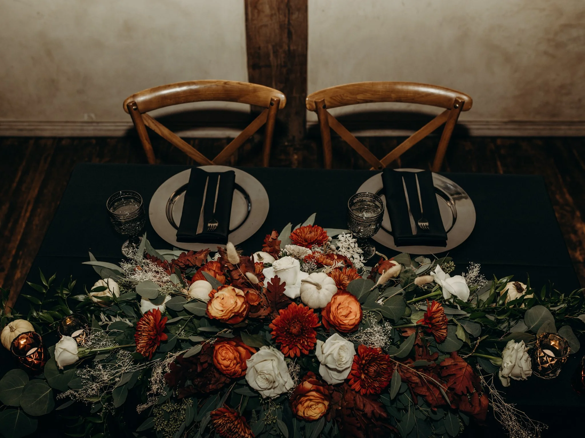 Sweetheart table with an orange and white fall garland and white pumpkins