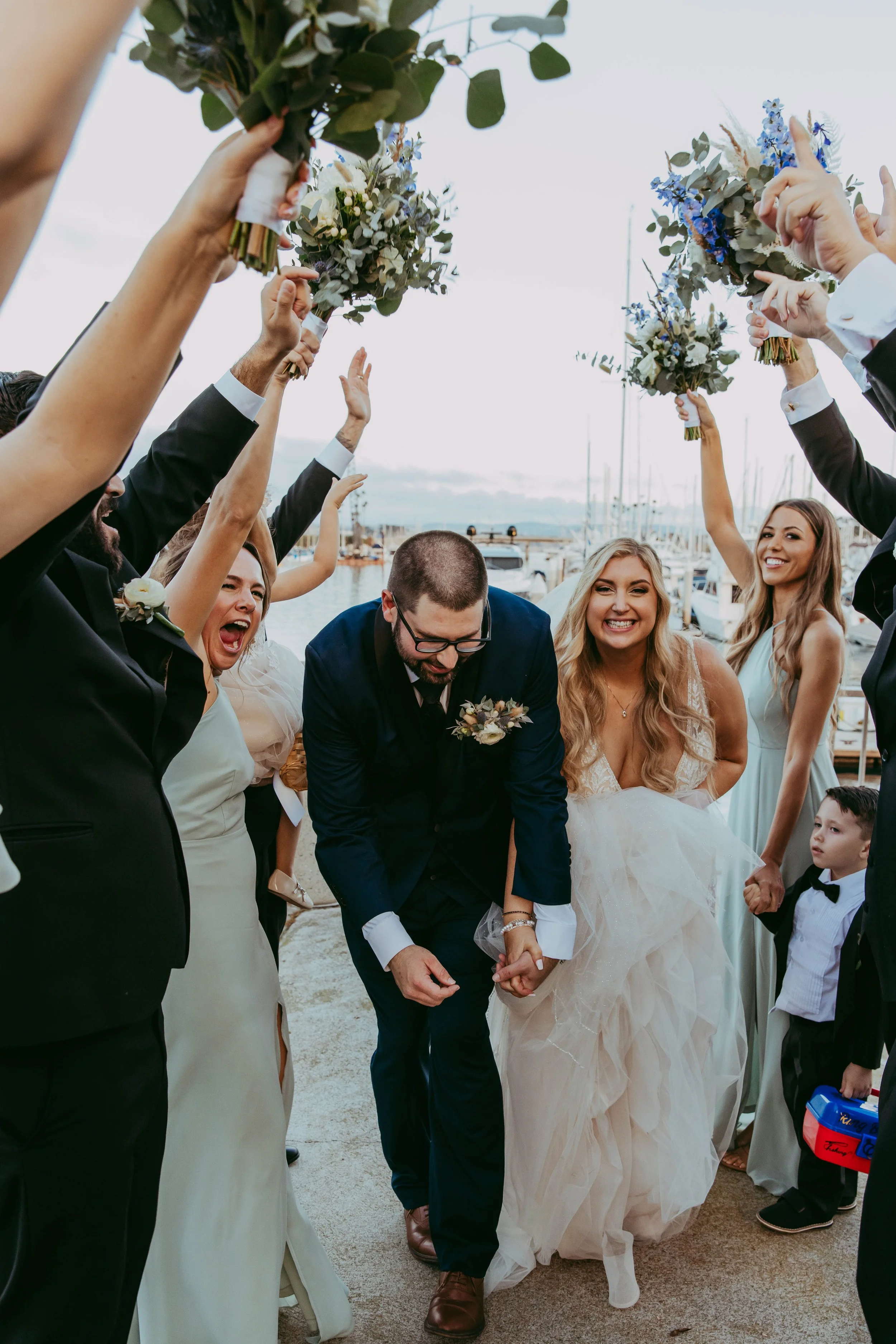 Newlyweds exit through a tunnel of raised bouquets at their Dana Point Yacht Club wedding