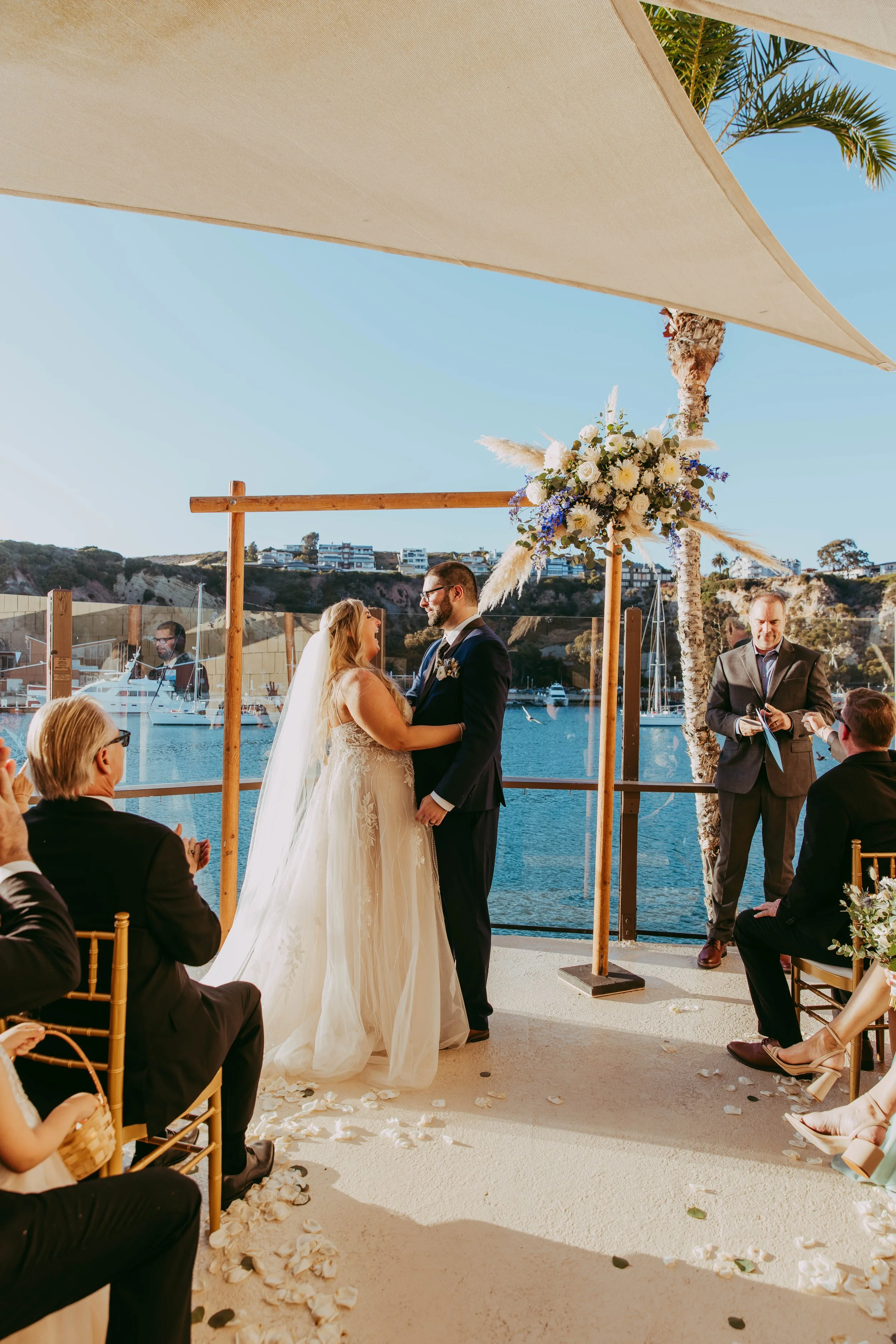 Bride and groom exchange vows at a waterfront Dana Point Yacht Club ceremony over the harbor