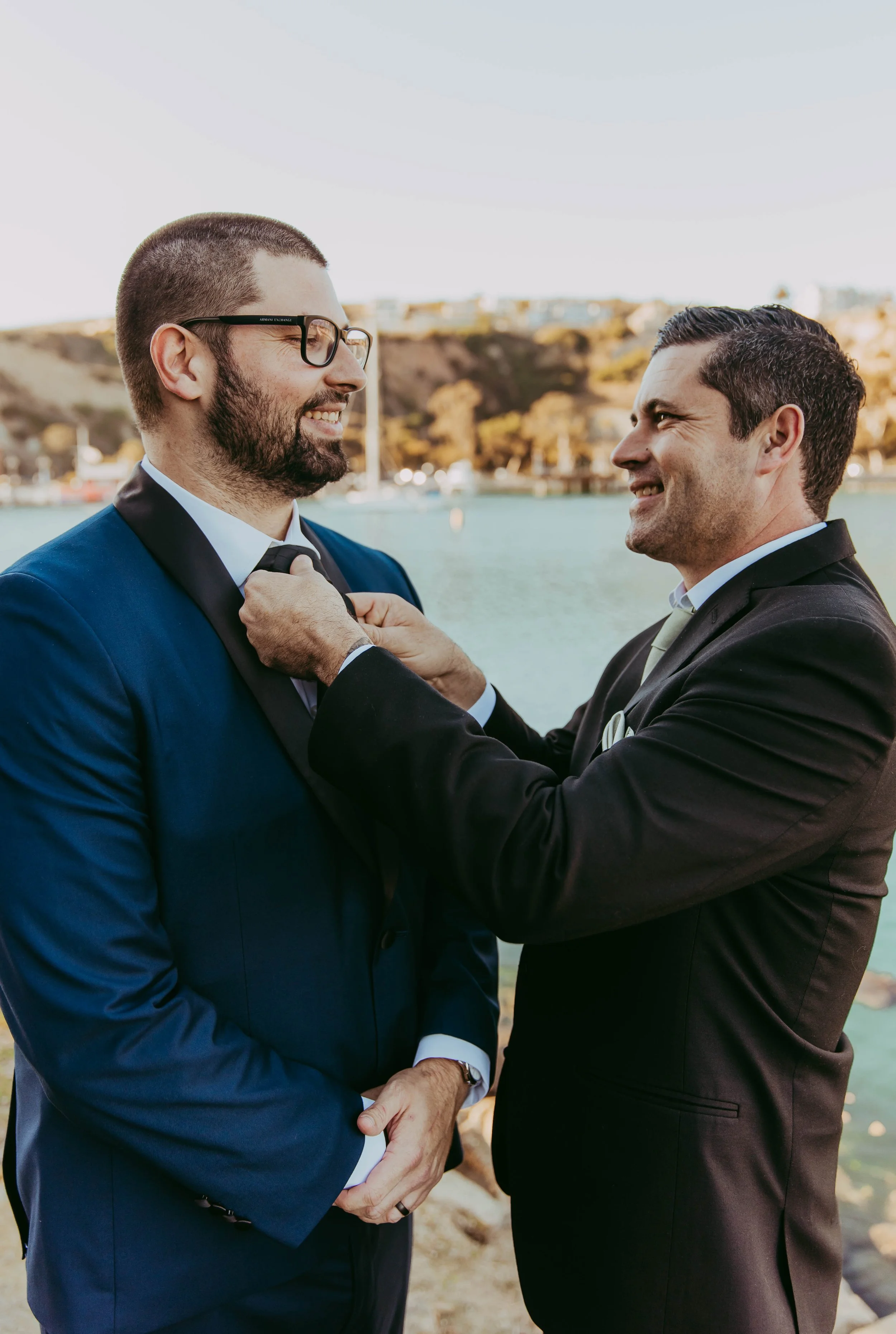 Groom has his tie fixed by the harbor before a Dana Point Yacht Club wedding
