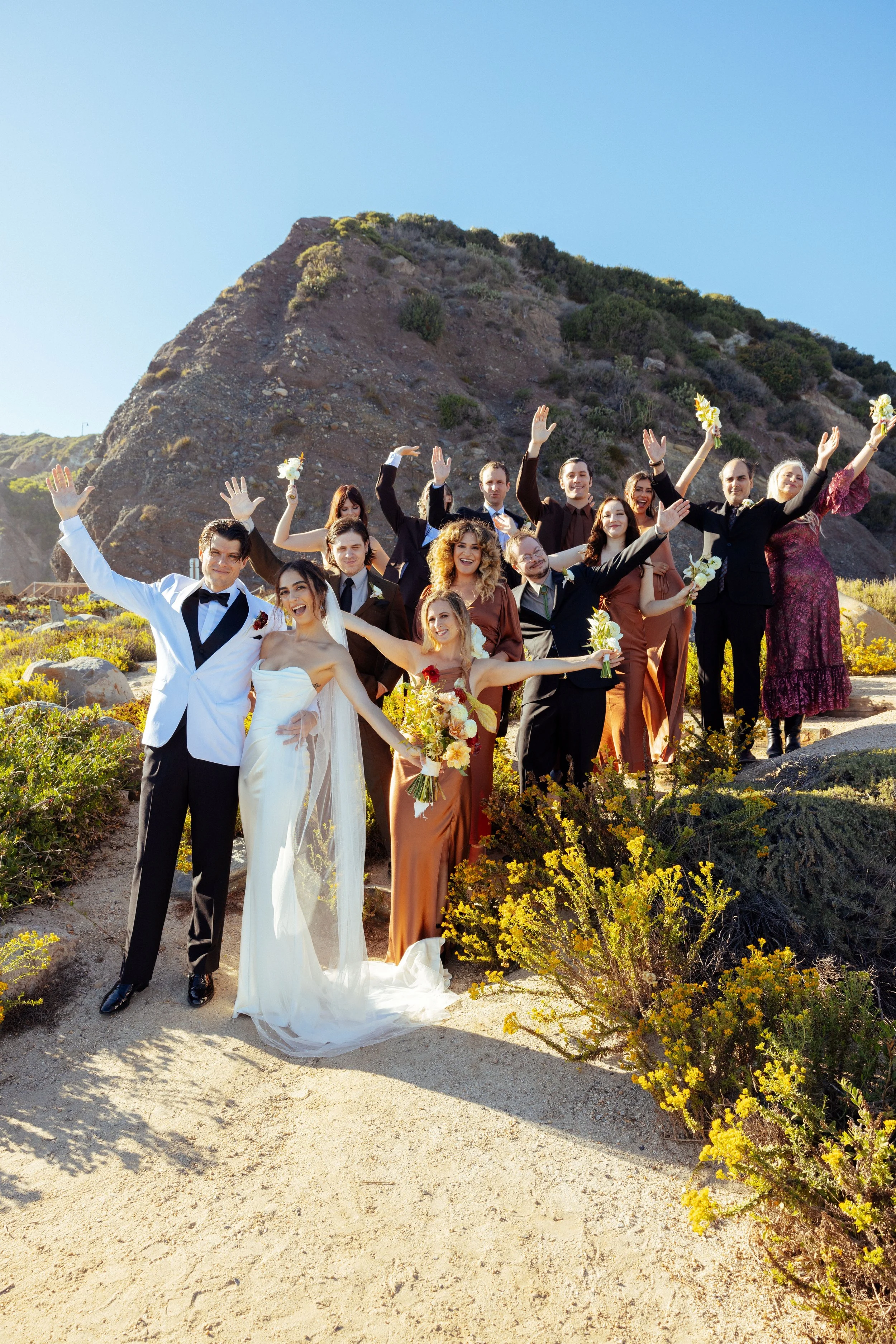 Wedding party cheers on a coastal hillside trail above Dana Point