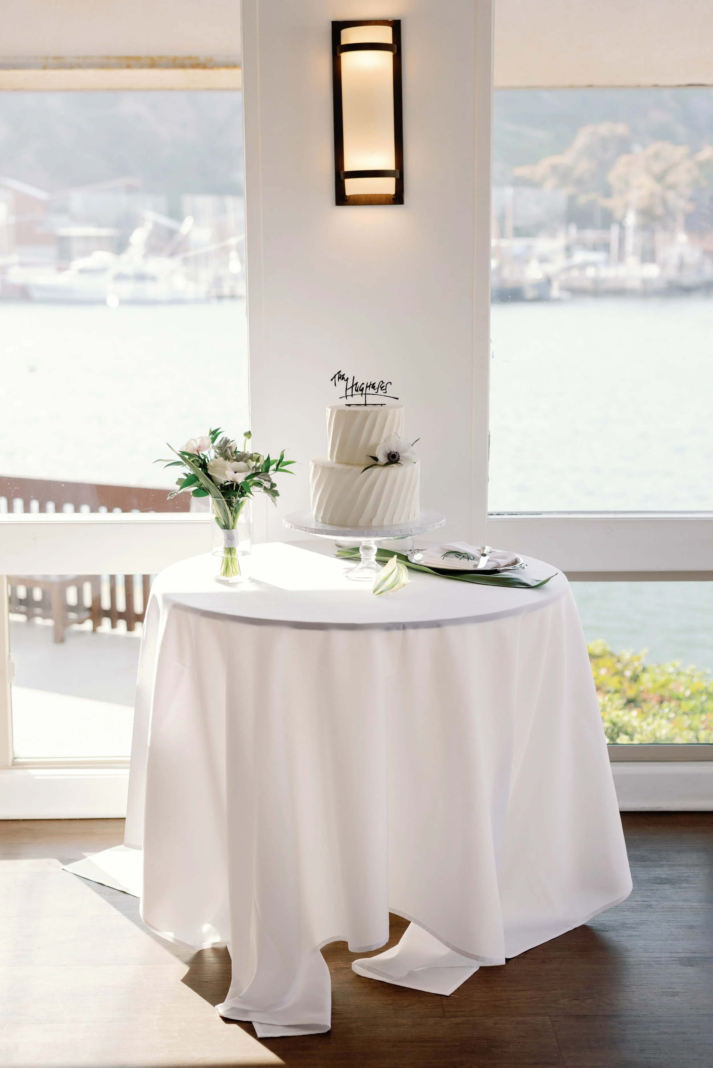 Two-tier wedding cake on a harbor-view table at a Dana Point Yacht Club reception