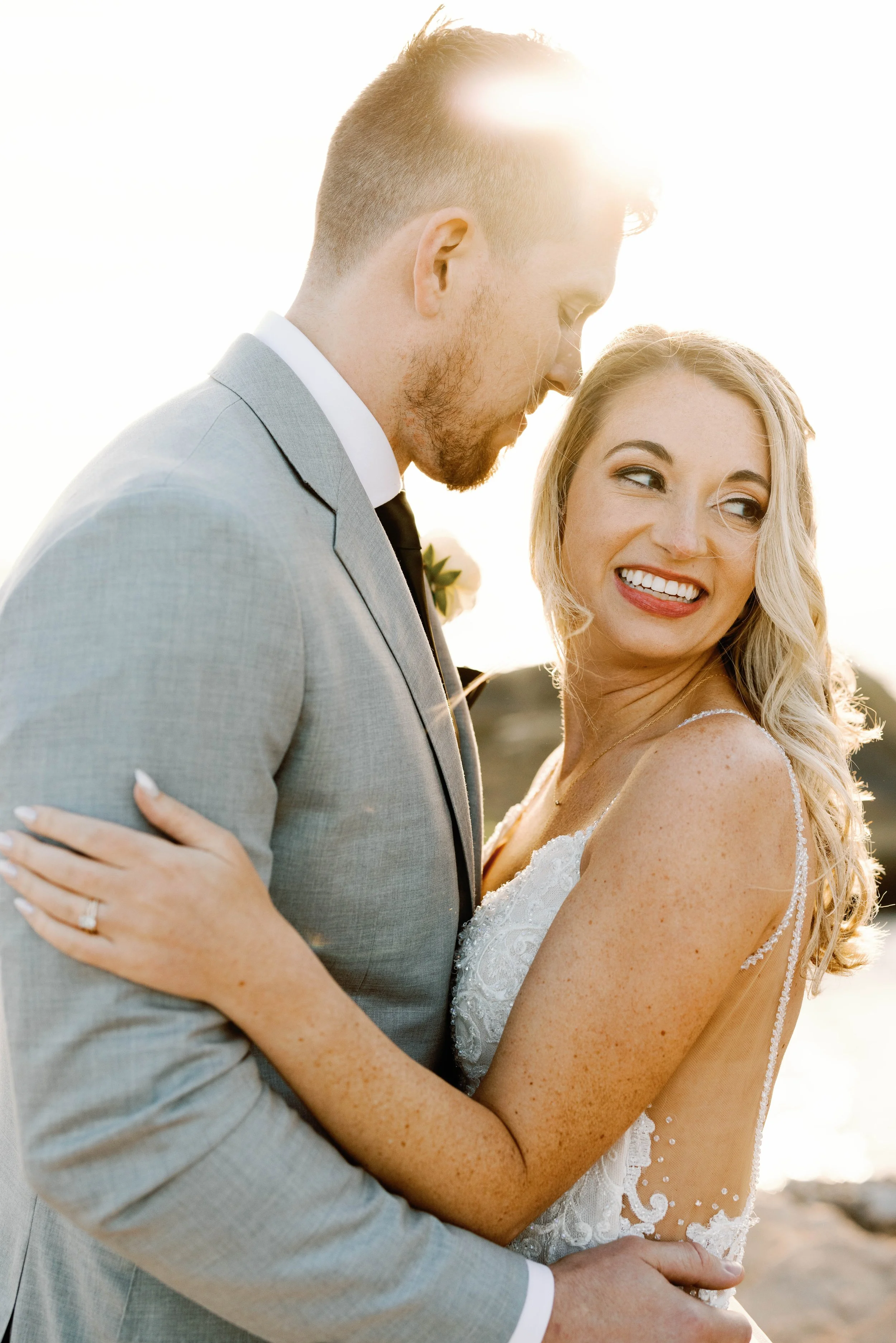 Backlit bride and groom share a laugh at golden hour on the Dana Point coast