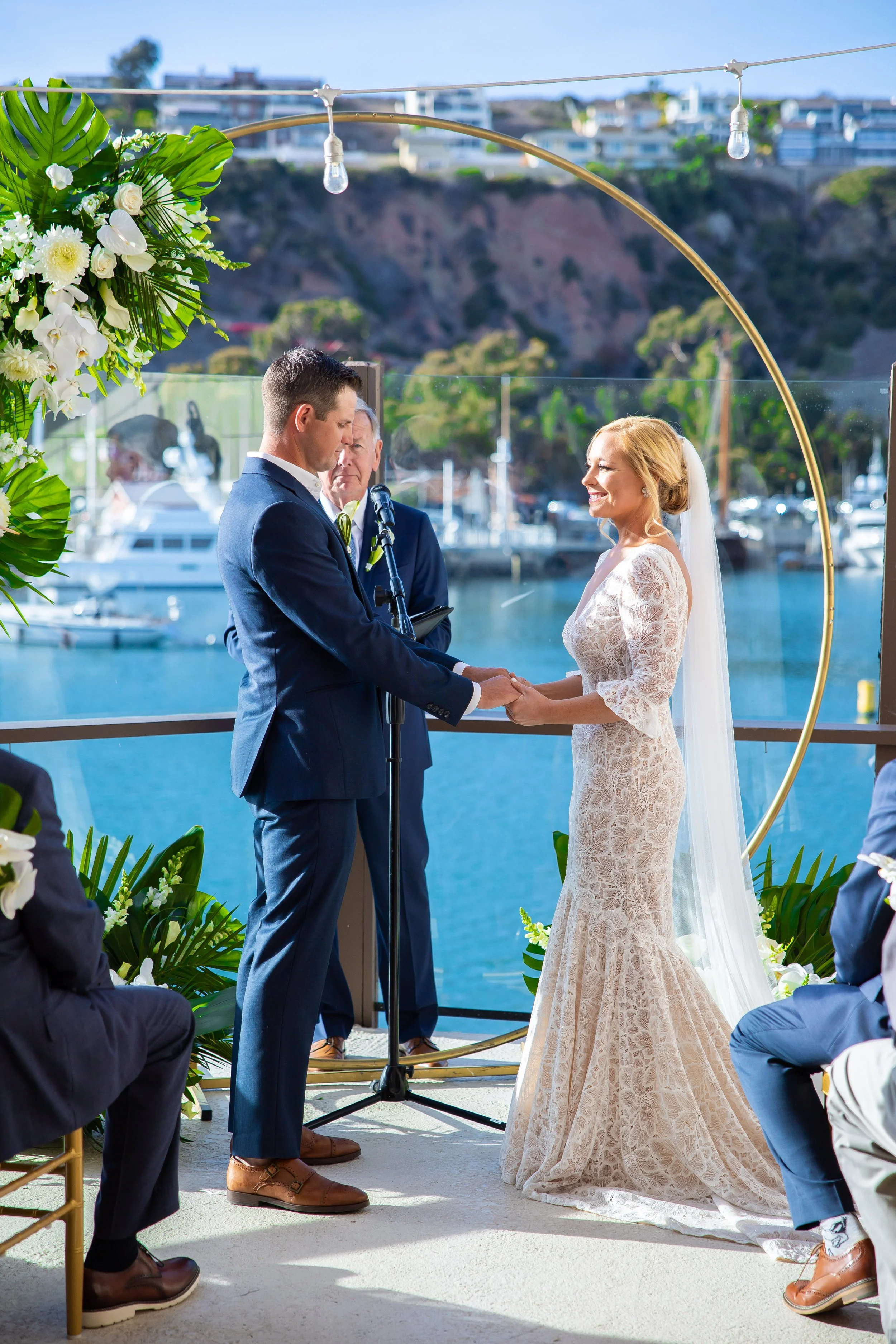 Couple holds hands at a harbor-front ceremony at Dana Point Yacht Club