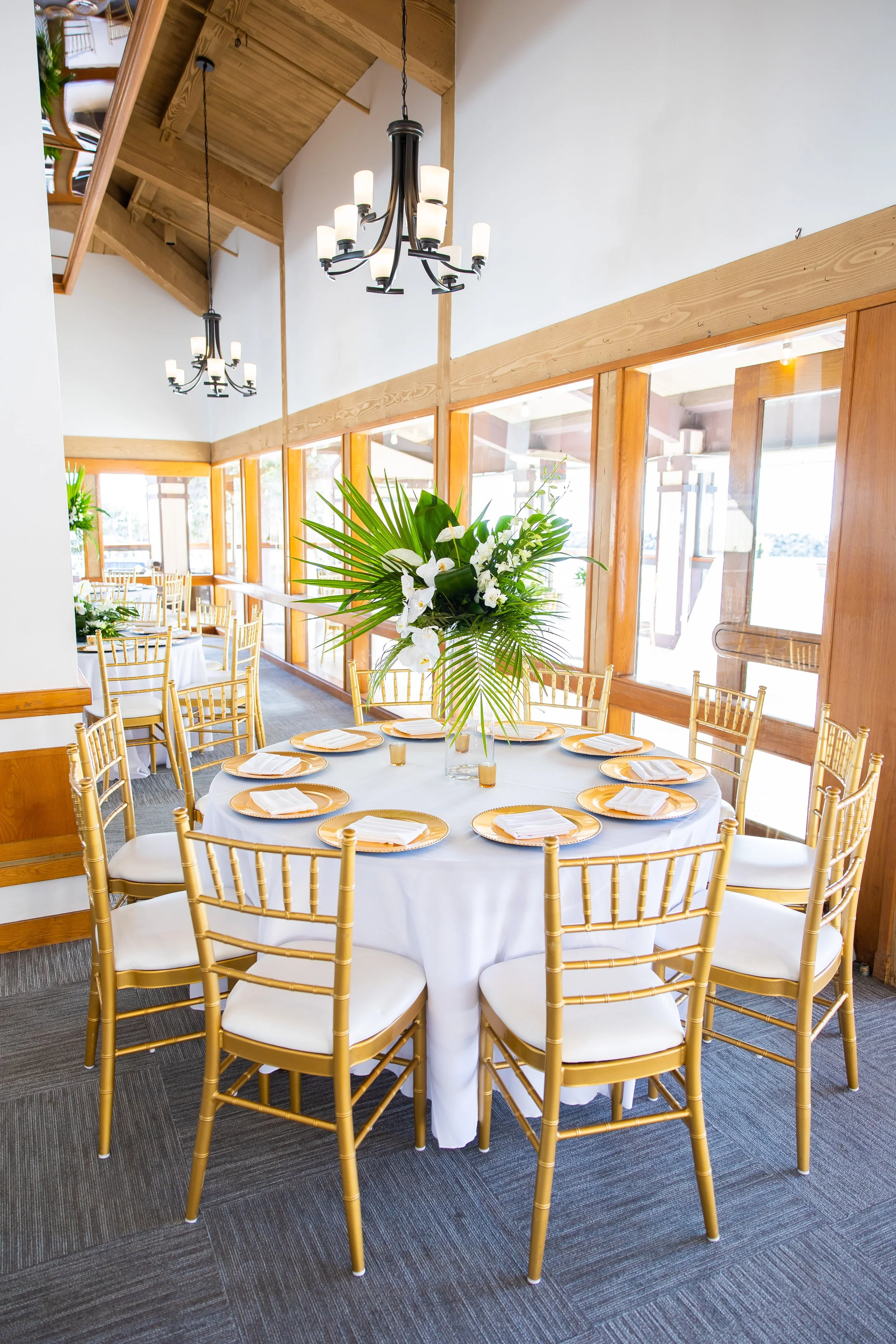 Harbor-view reception room with gold chairs and tropical centerpieces at Dana Point Yacht Club