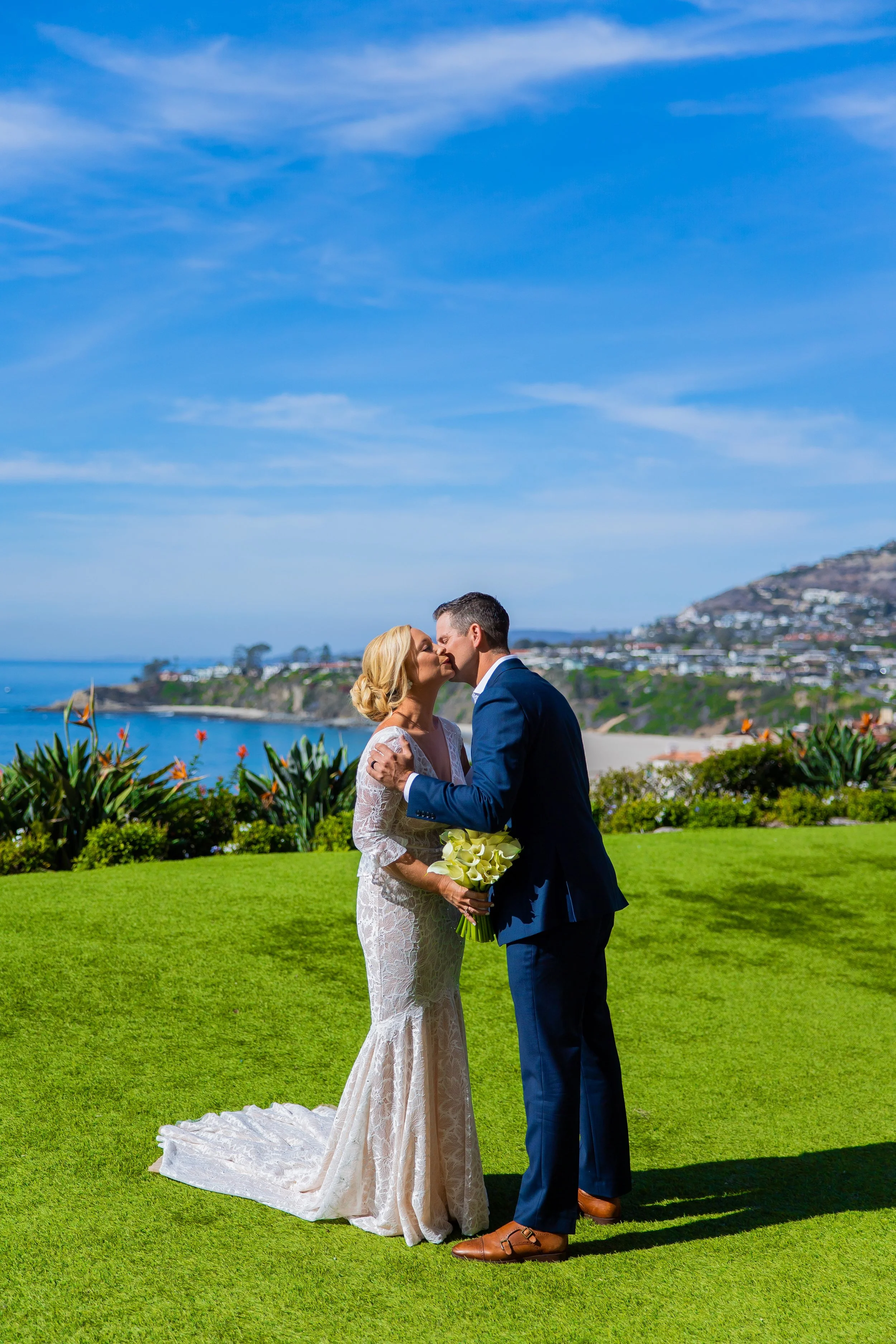 Couple kisses on an ocean-view bluff lawn during their Dana Point wedding