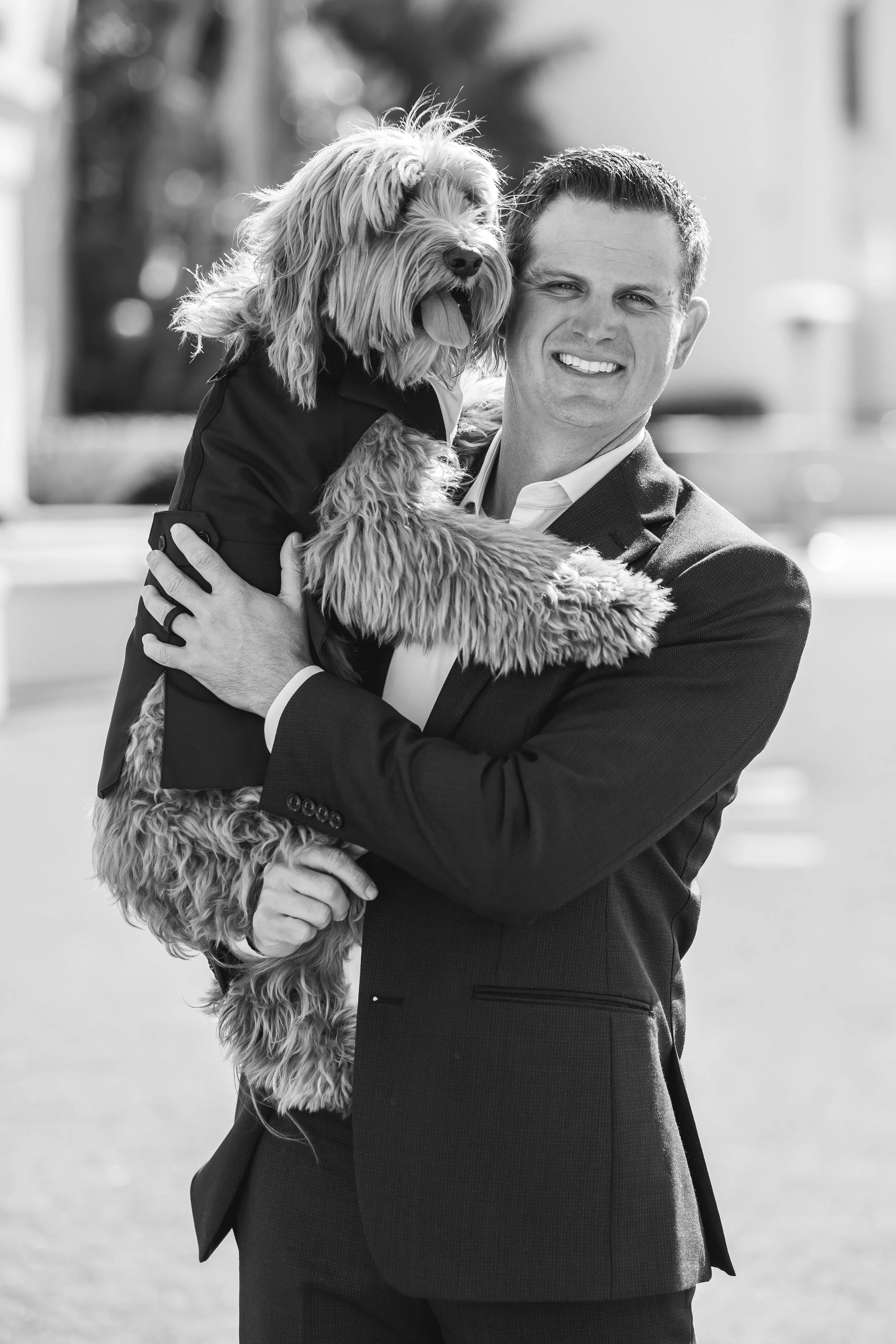 Groom holds the couple's dog before a Dana Point wedding, black and white