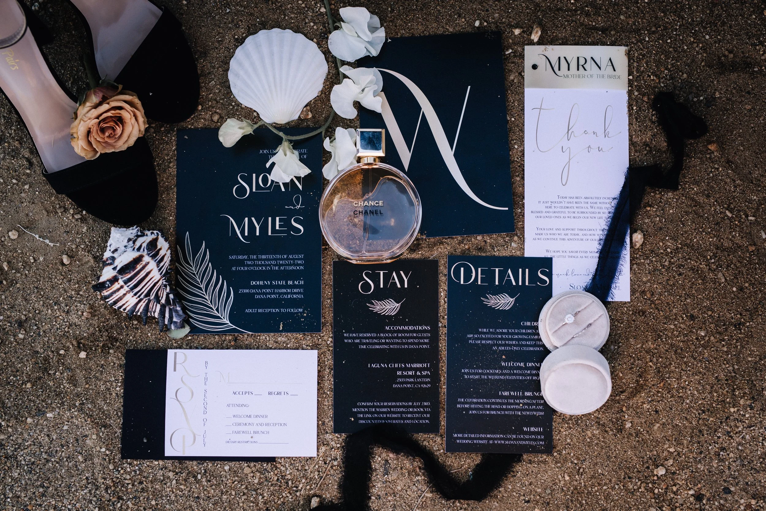 Black and gold beach wedding invitation suite with seashells and Chanel on the sand