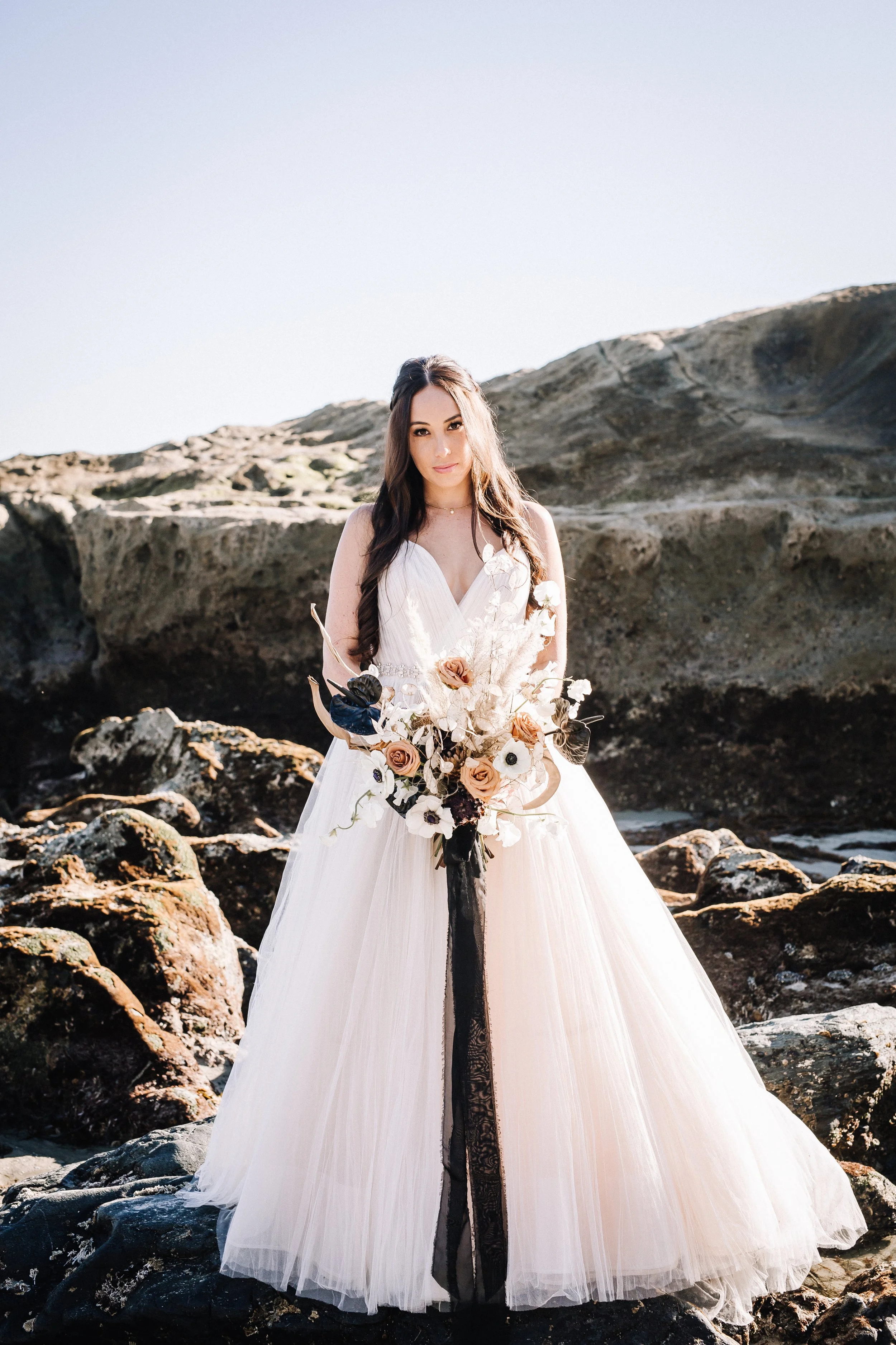 Bride in a blush tulle gown with a black sash at an alternative Dana Point beach wedding