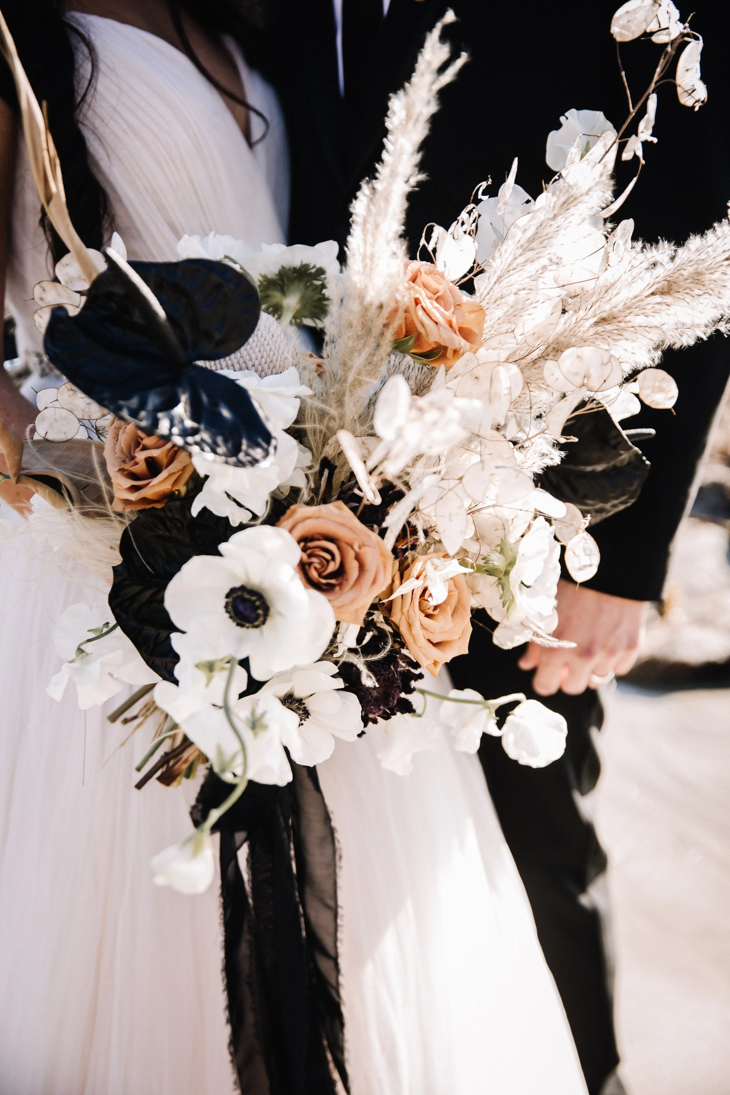 Unique wedding bouquet of white anemones, caramel roses, pampas and trailing black ribbon