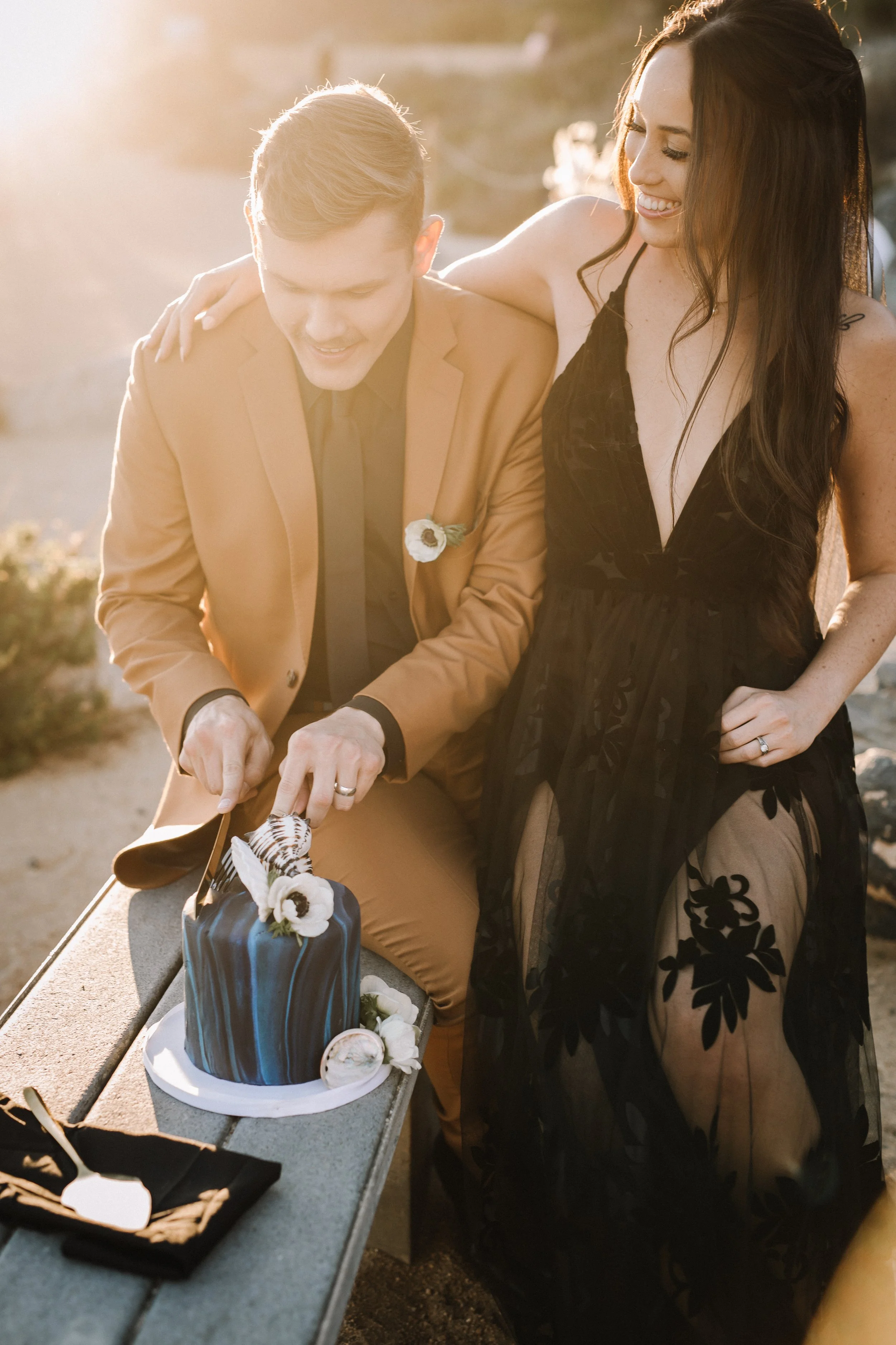 Couple cut a navy wedding cake at sunset at an alternative Dana Point beach wedding