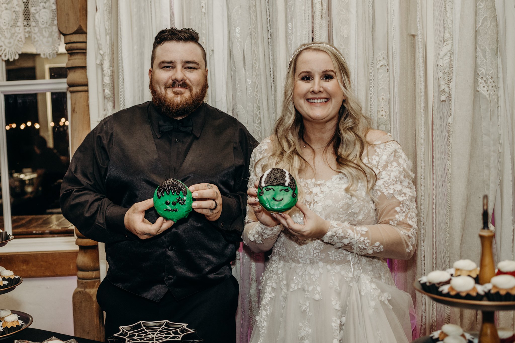 Couple holding Frankenstein donuts instead of cake at their Halloween wedding