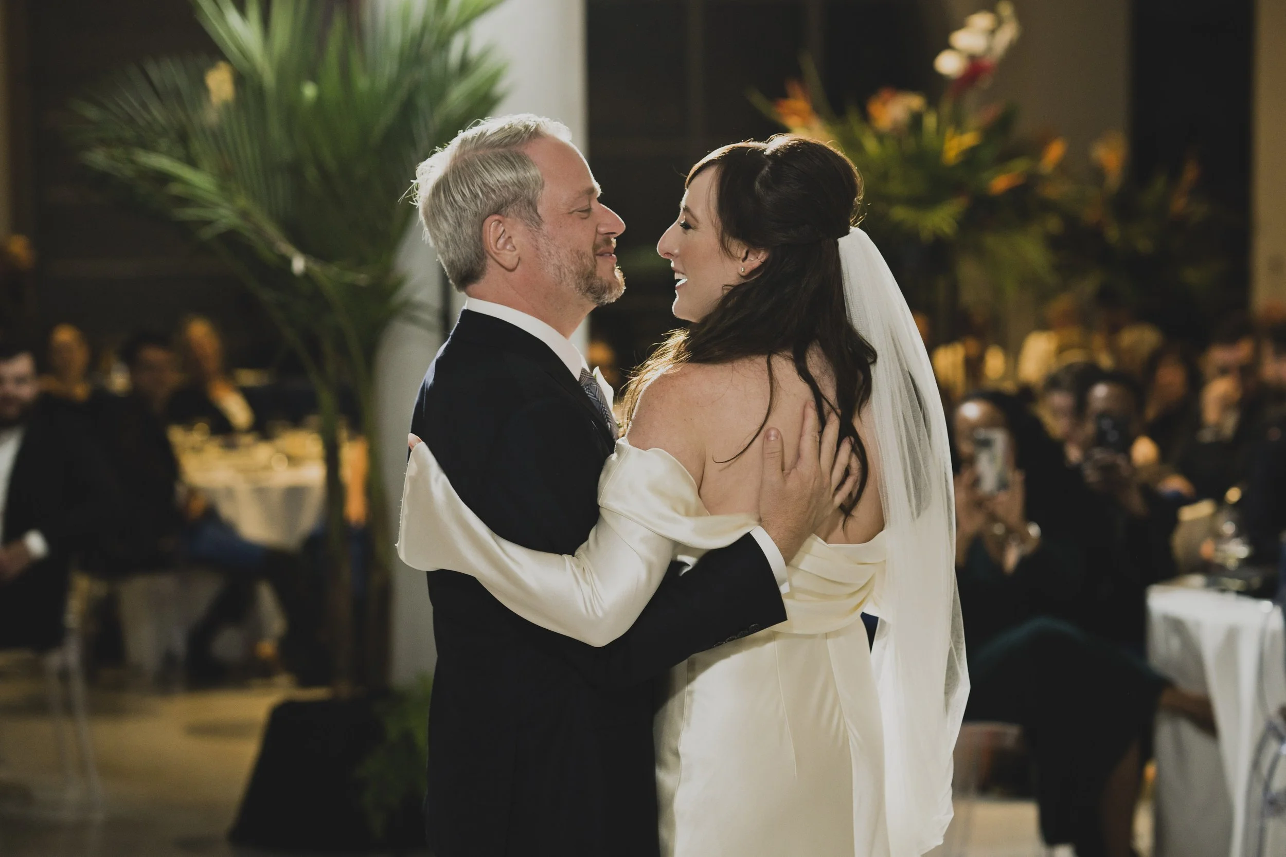 Bride twirling beneath the groom's raised hand during their first dance at an elegant modern museum wedding reception.