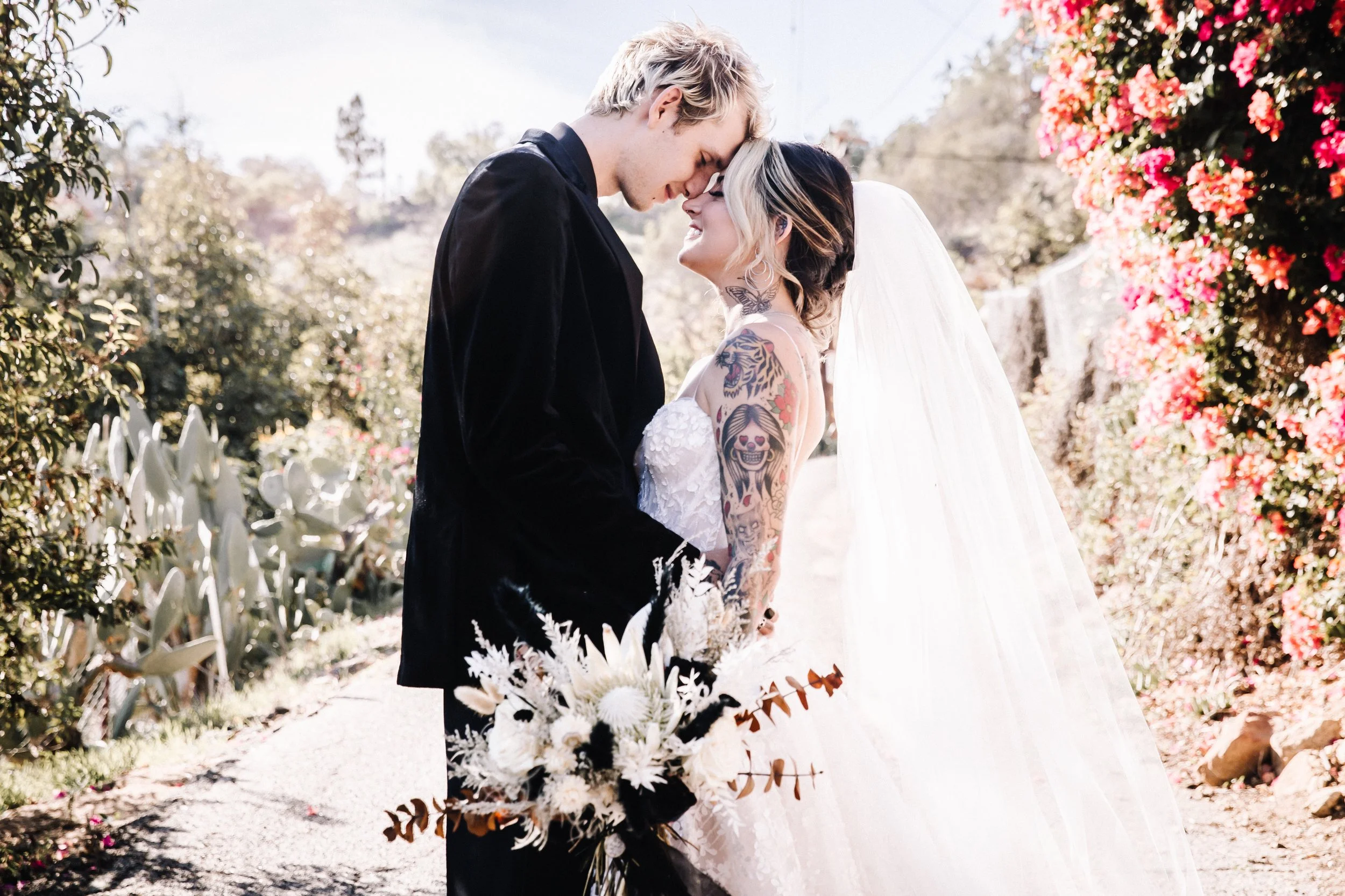 Bride and groom in front of a cactus garden during romantic portraits from their elegant outdoor Halloween wedding